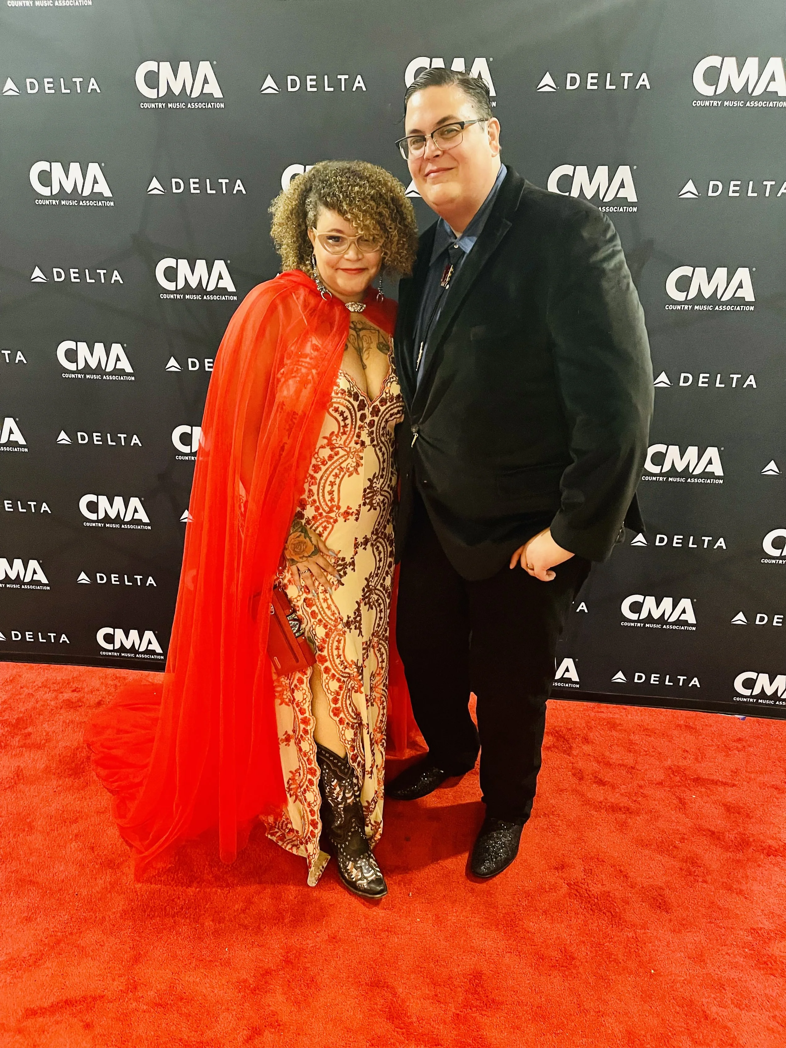 Nourich, LLC founders Briana McCrae Carr & Frank Carr dressed in formal attire posing on a red carpet at a CMA event with a black backdrop featuring CMA and Delta logos for the Creativets Feature