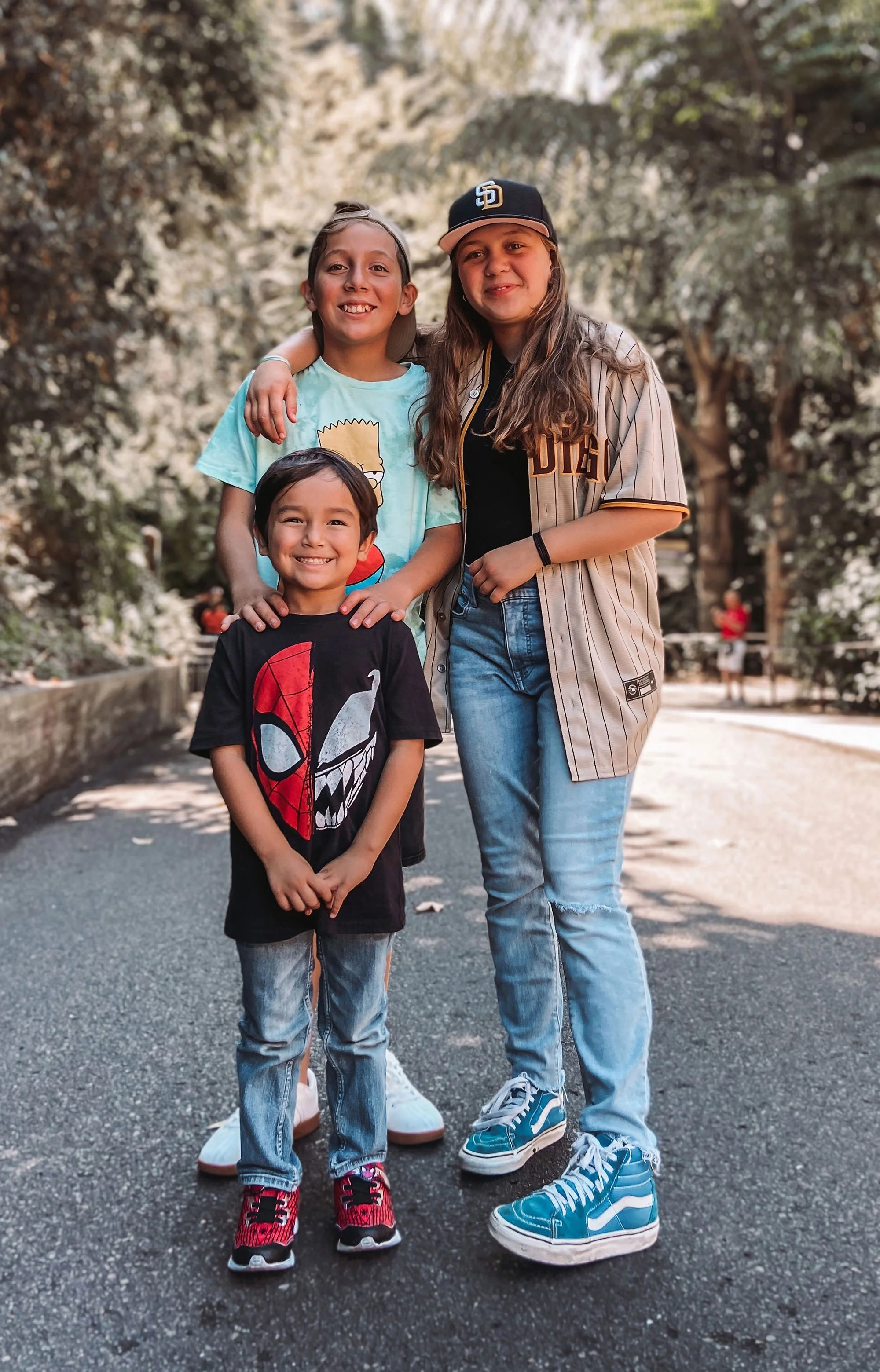 Three children smiling and standing together after their home has been restored by BAM.