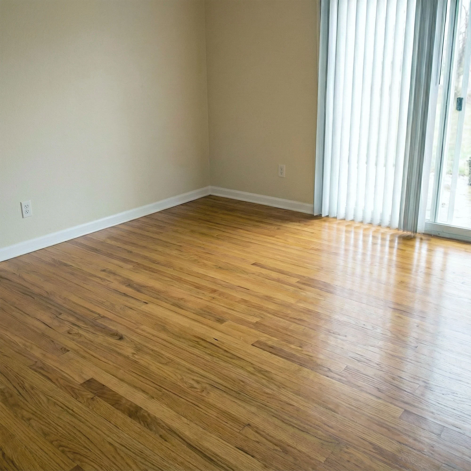 Before and after image of a BAM Restoration job that shows a pristine empty room with hardwood floor, beige walls, white baseboards, and a sliding glass door with vertical blinds.