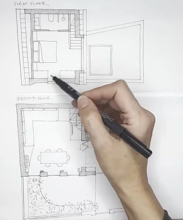 Drawing of a two-story house floor plan with a person sketching the upper level and lower level layout.