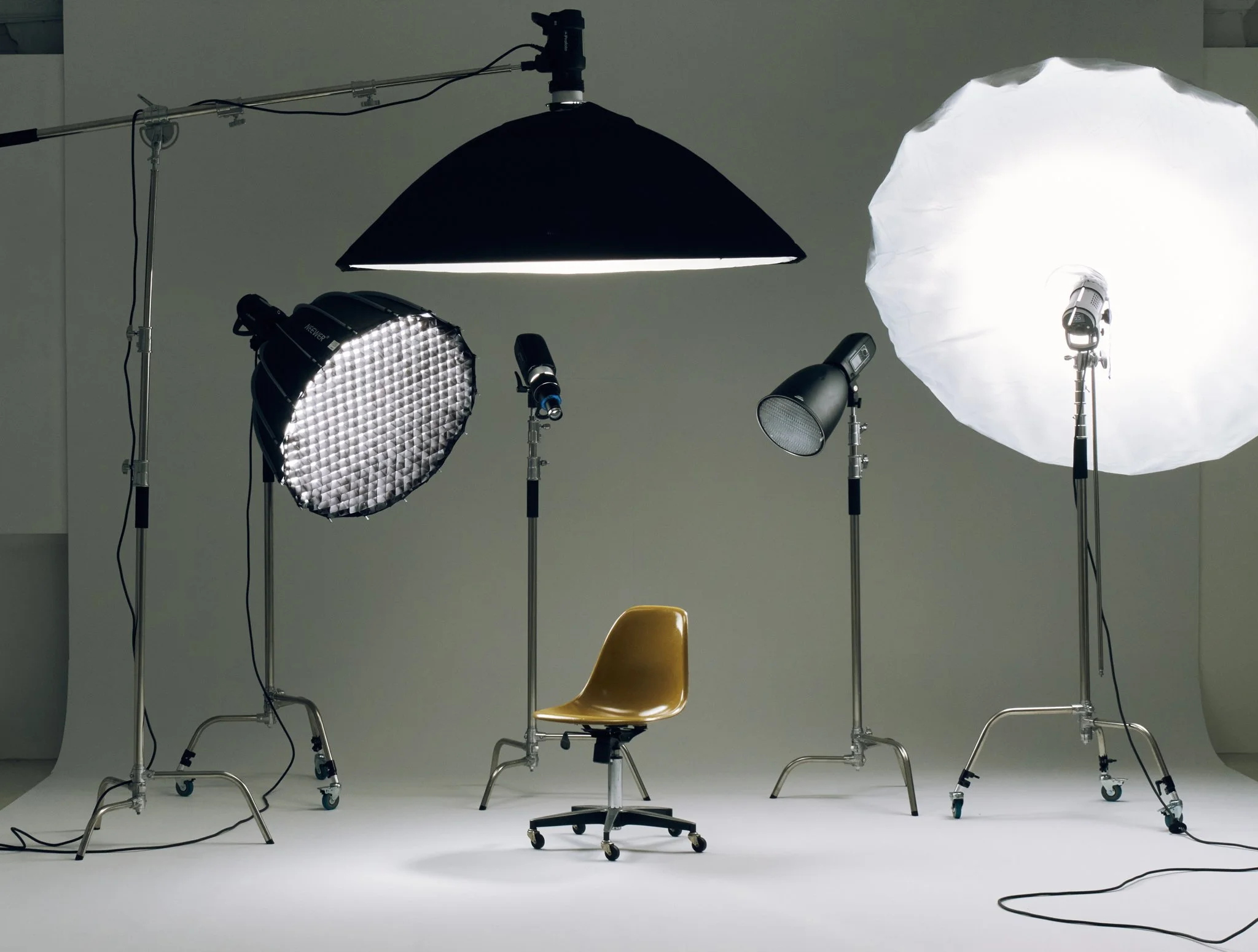 Photography studio with professional lighting equipment and a brown chair on a white background.