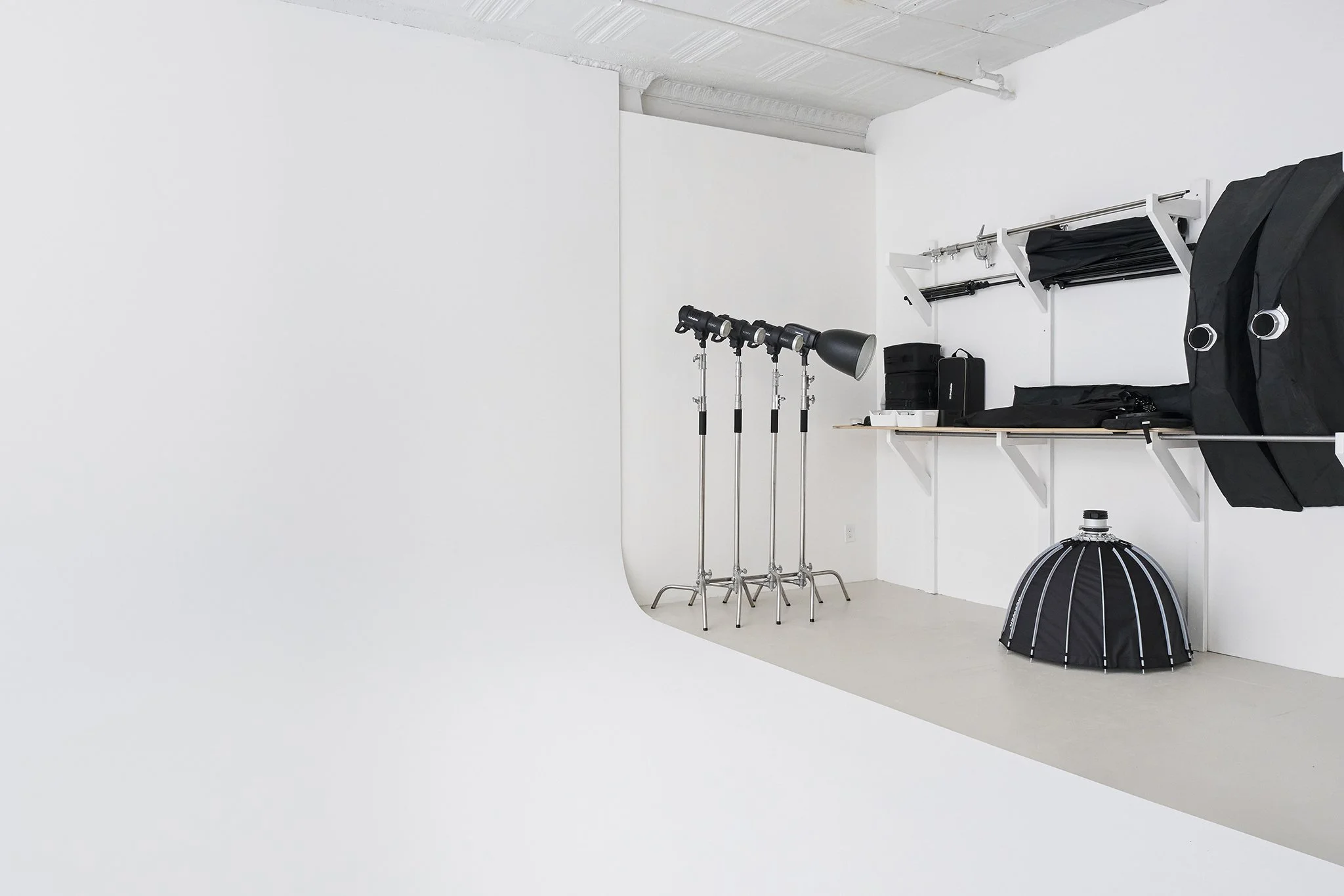 Photography studio with professional lighting equipment, backdrop, and props in a white room.