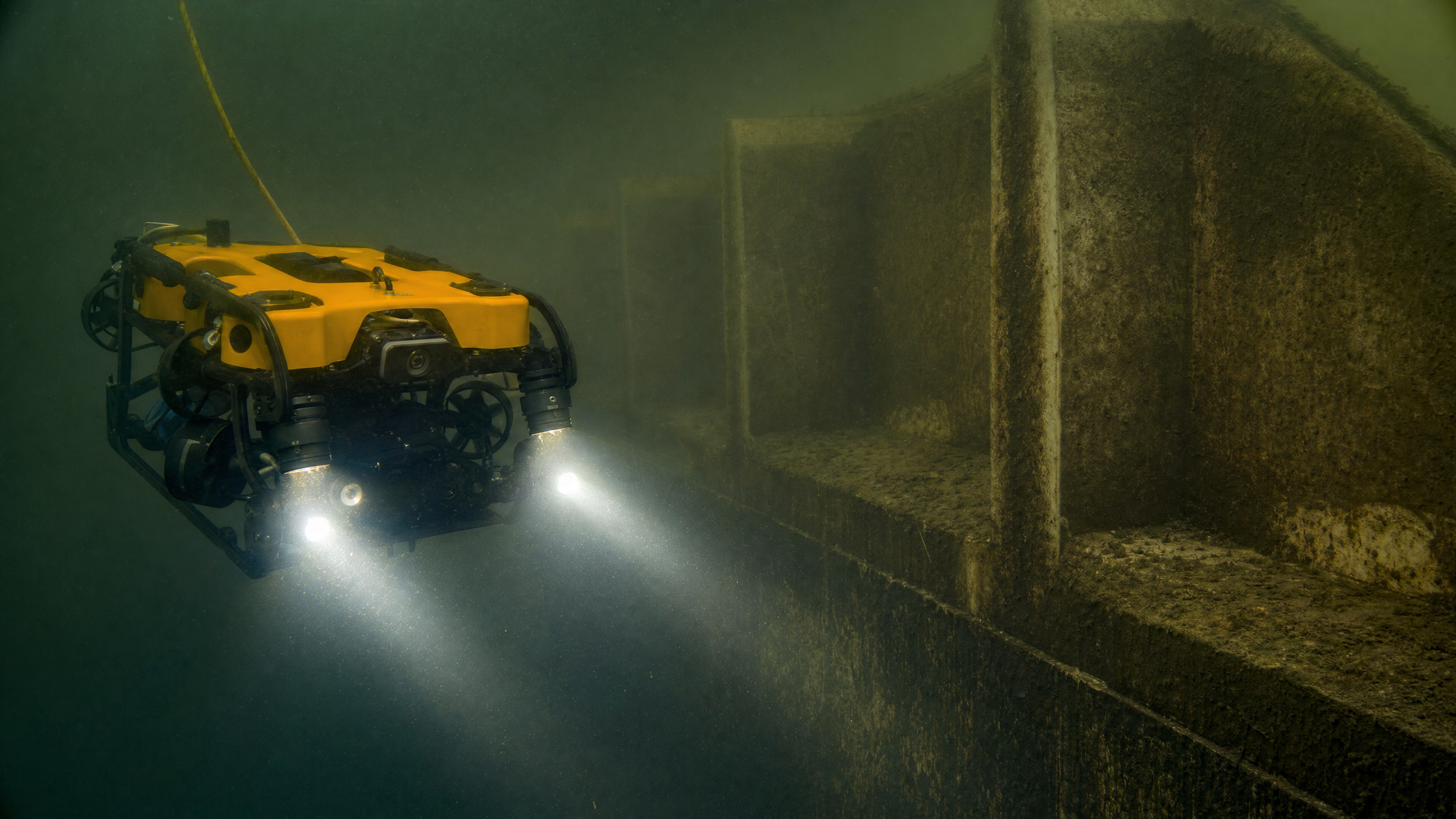 A yellow underwater ROV is inspecting a submerged structure in a tailings dam by DeepSky IQ.