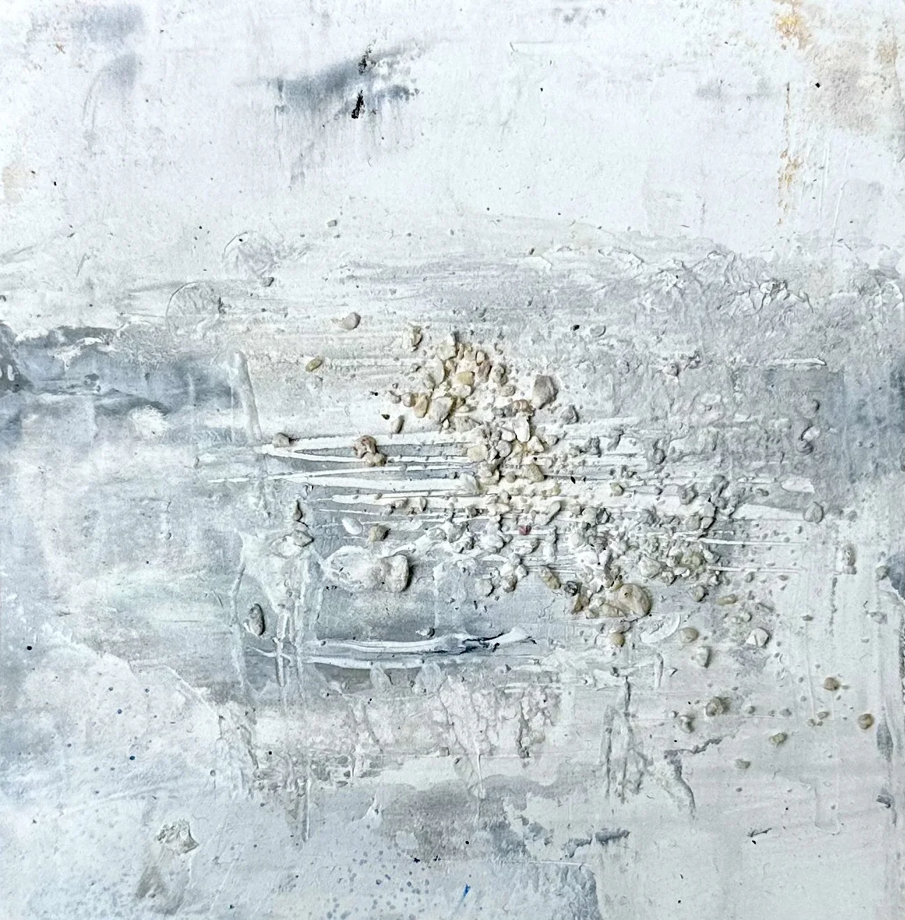 A weathered white wall with scattered paint chips, dust, and small lumps of plaster or debris on the surface.