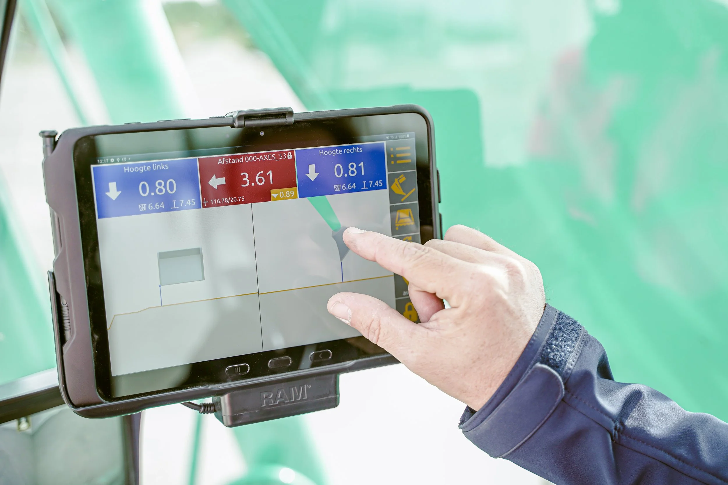 Close-up of a person's hand operating a tablet with data and graphs on a screen, likely on a farm or agricultural setting.