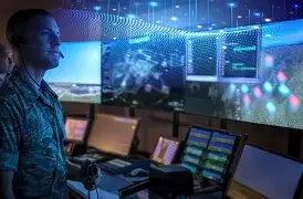 A man at a control center with multiple monitors displaying data and visualizations.