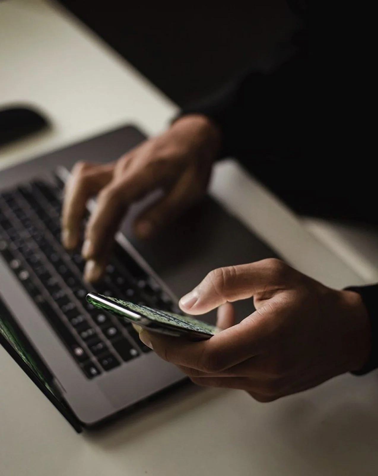 A group of people sitting around a wooden table with notebooks, pens, and papers, engaged in a discussion.
