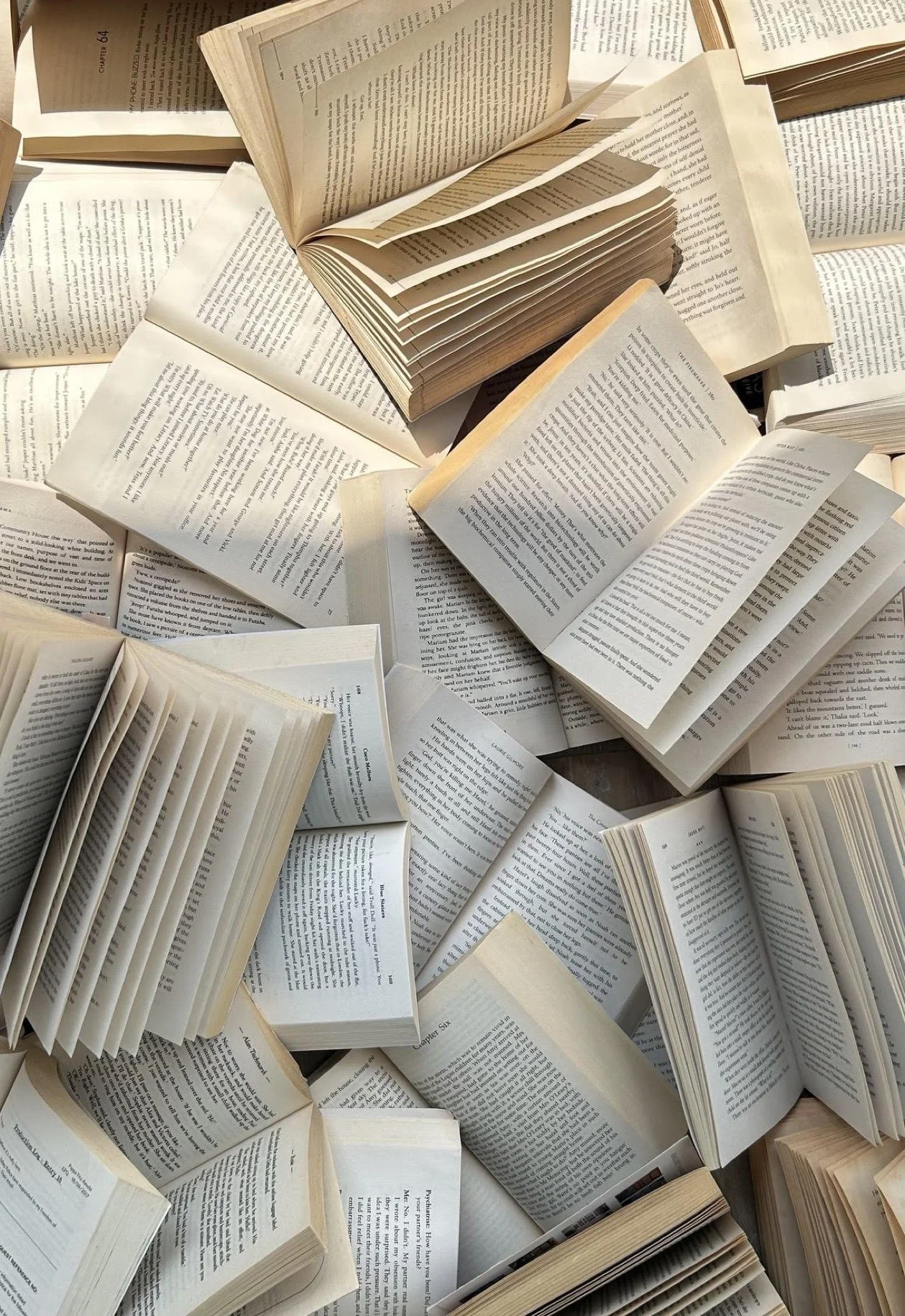A hand holding a stack of ten books against a plain white background.