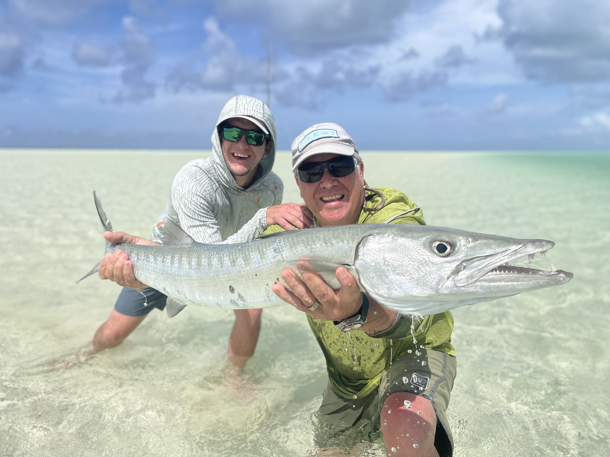Anglers holding a large barracuda caught on the flats of Grand Bahama, Bahamas.
