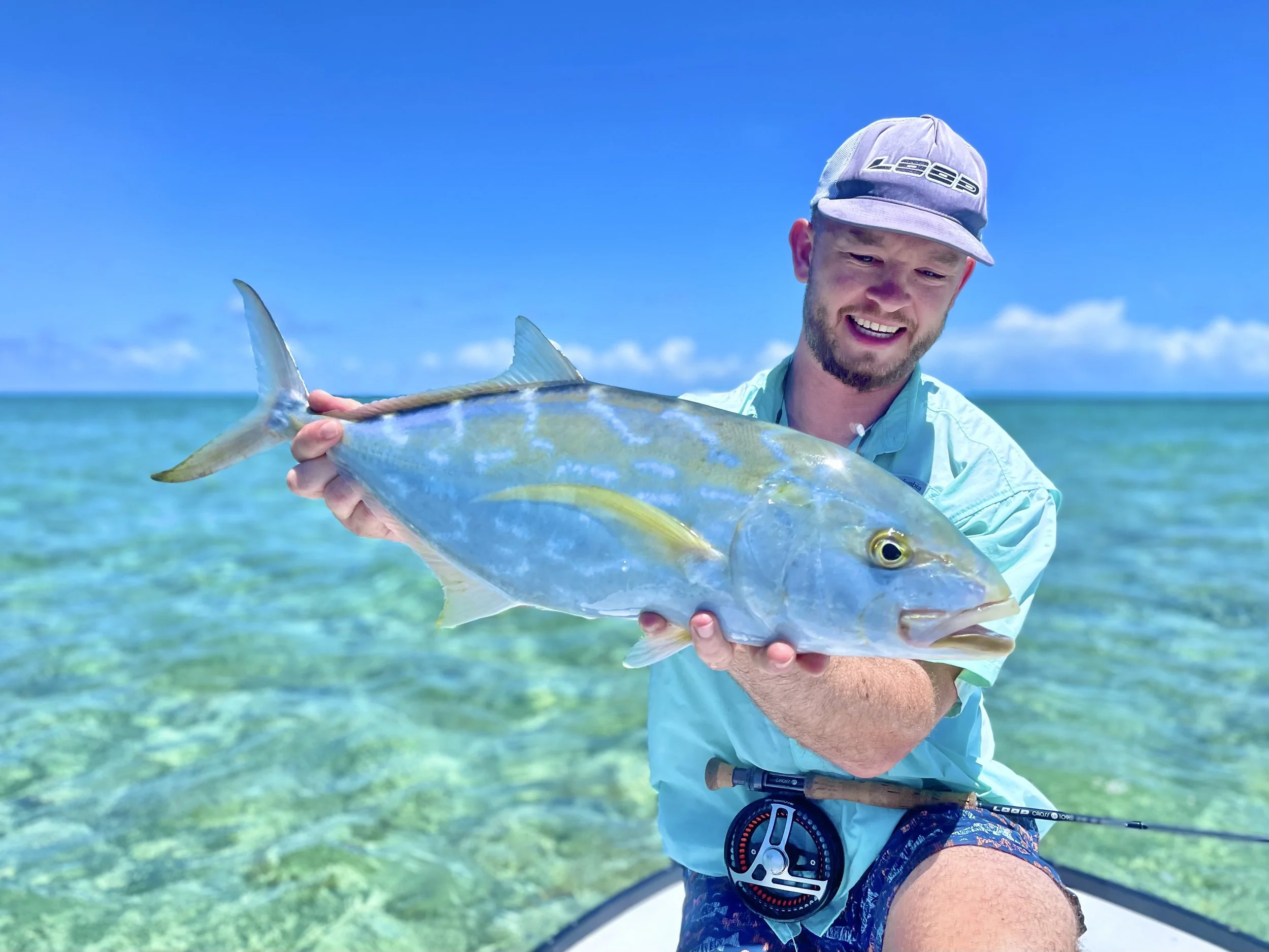 Fly angler holding a yellow jack caught in shallow waters of Grand Bahama, Bahamas.