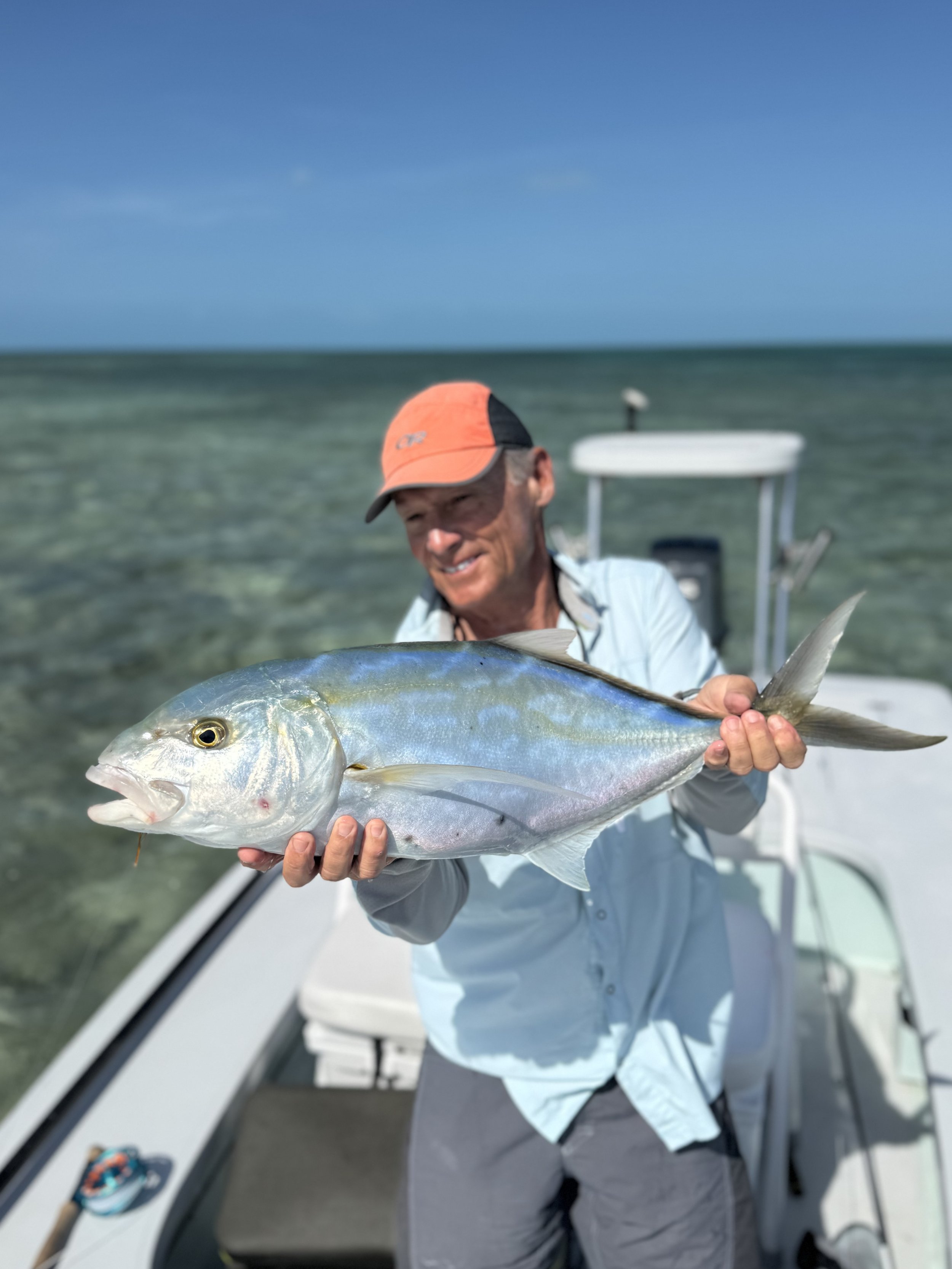 Angler holding a large yellow jack aboard a flats fishing boat in Grand Bahama, Bahamas.
