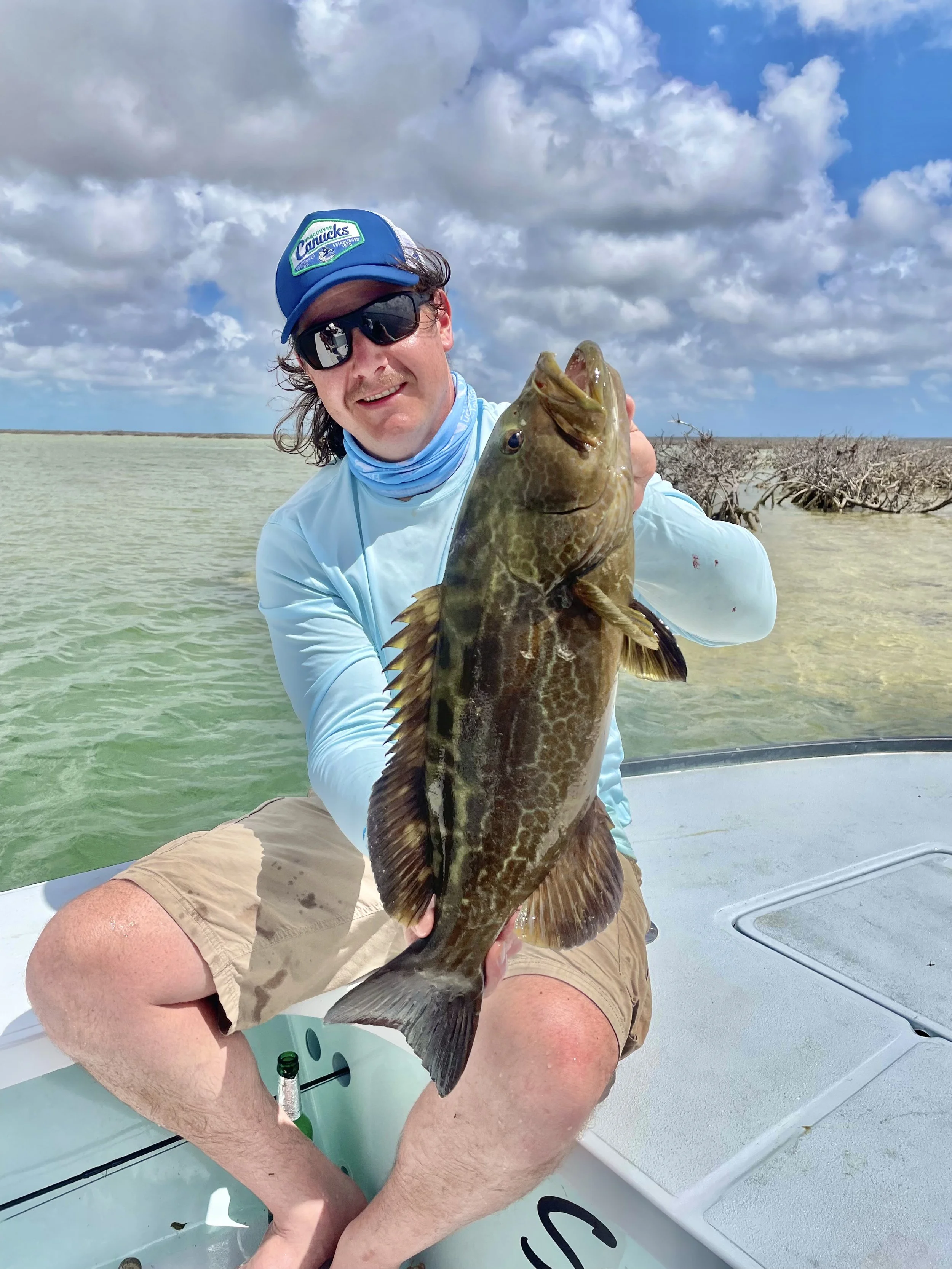 Angler holding a large grouper from the shallow waters of Grand Bahama, Bahamas.