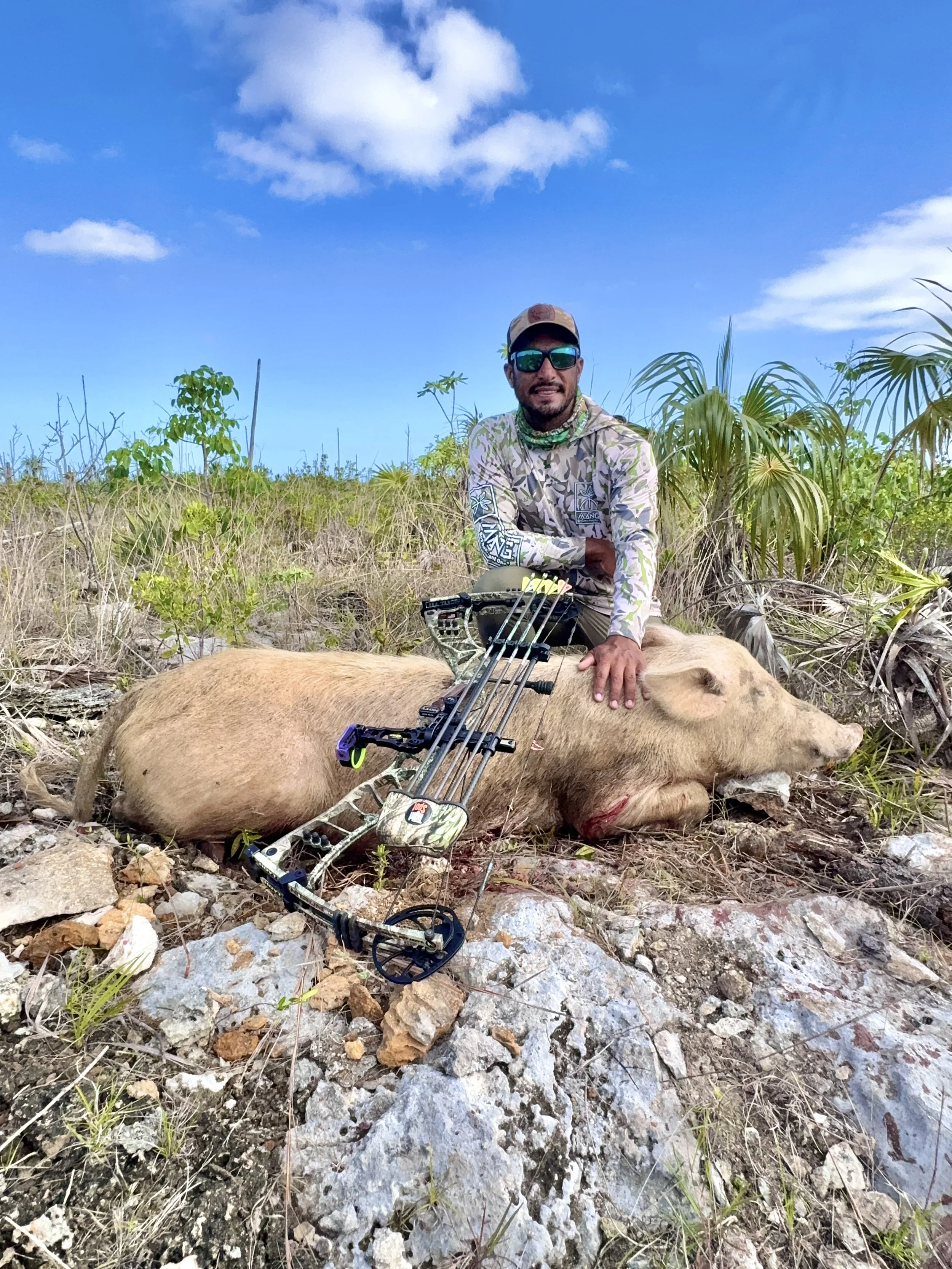 Bowhunter posing with a harvested wild hog in the bush of Grand Bahama.