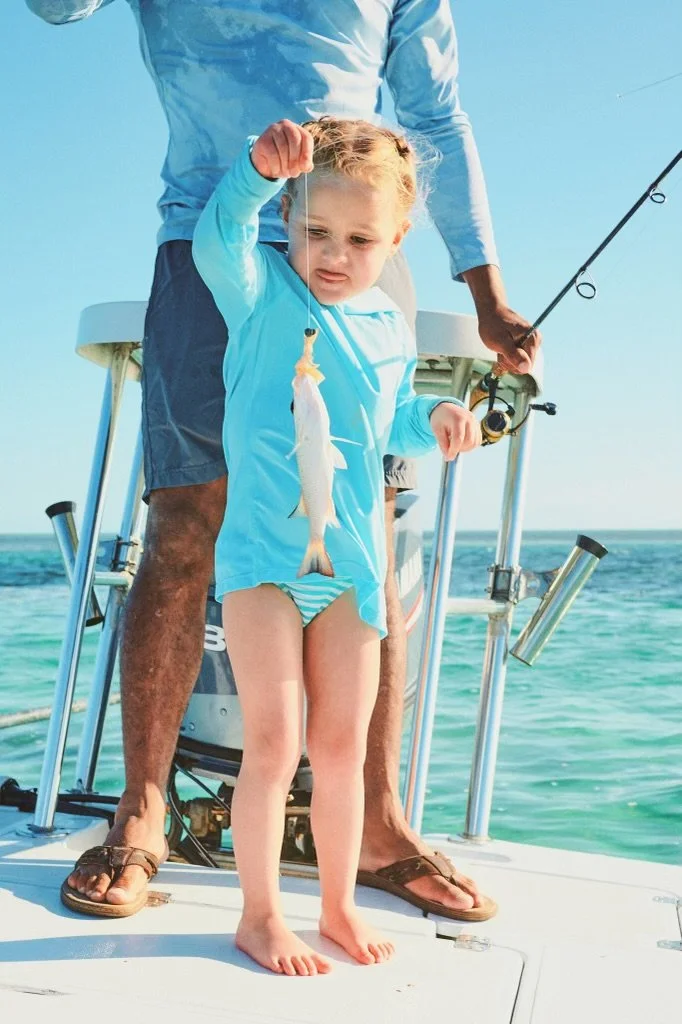 Young angler holding a freshly caught fish during a family fishing trip in Grand Bahama, Bahamas.