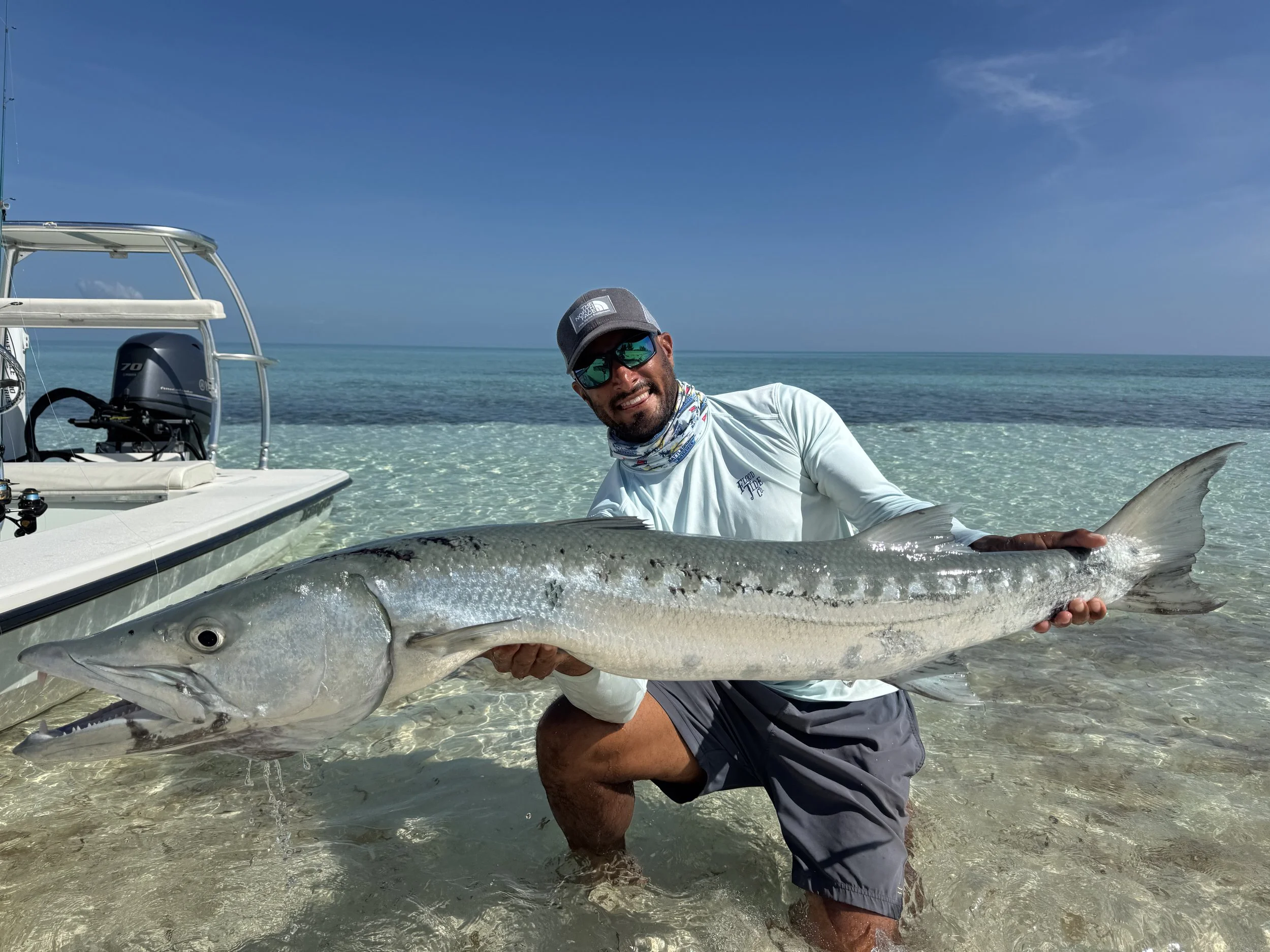 Angler holding a trophy barracuda while light tackle fishing the shallow waters of Grand Bahama, Bahamas.