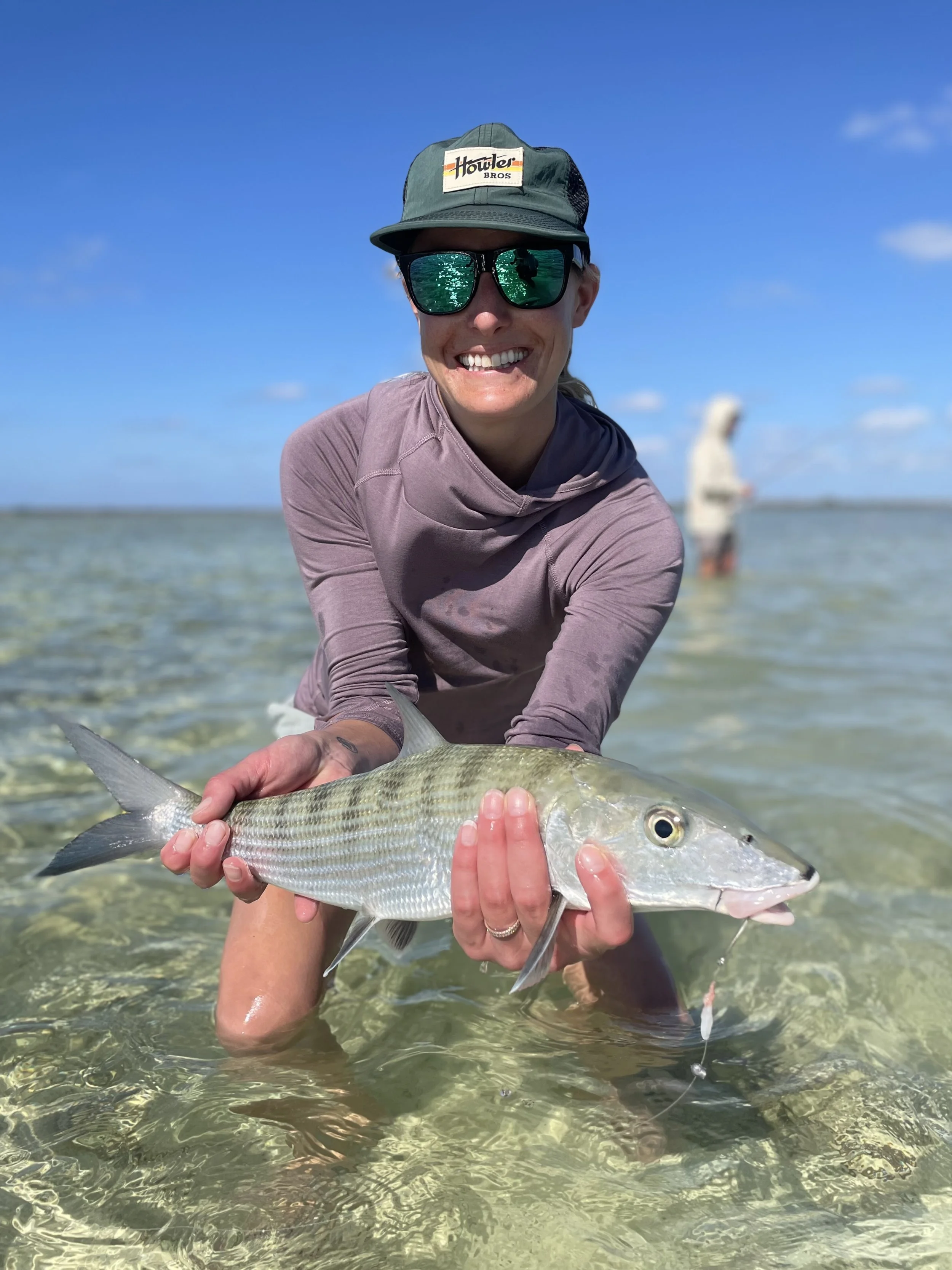 Angler holding a bonefish while flats fishing the clear shallow waters of Grand Bahama.