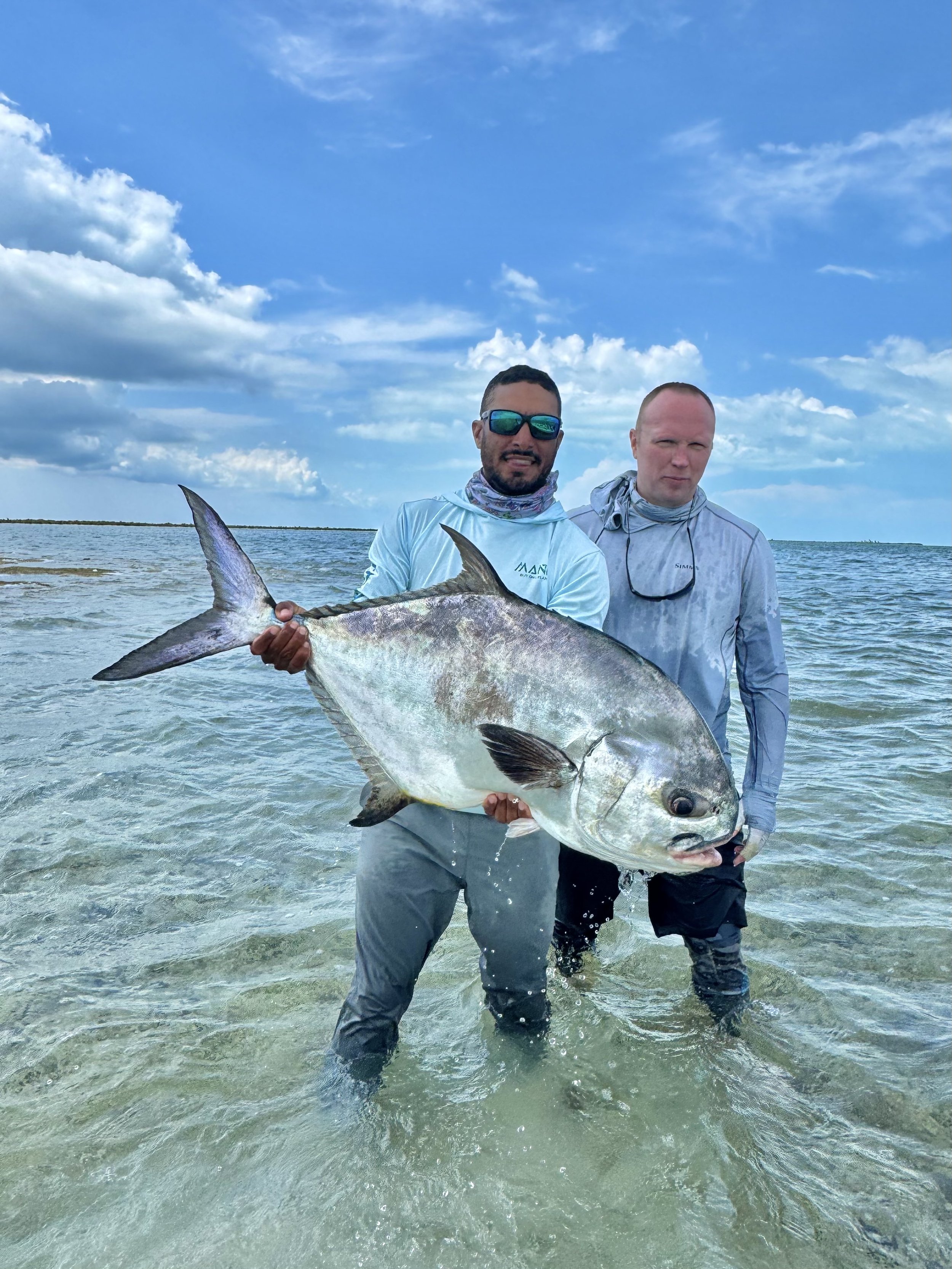 Angler and guide Justin Lewis holding a possible world record permit caught on fly during a successful flats fishing trip in Grand Bahama.