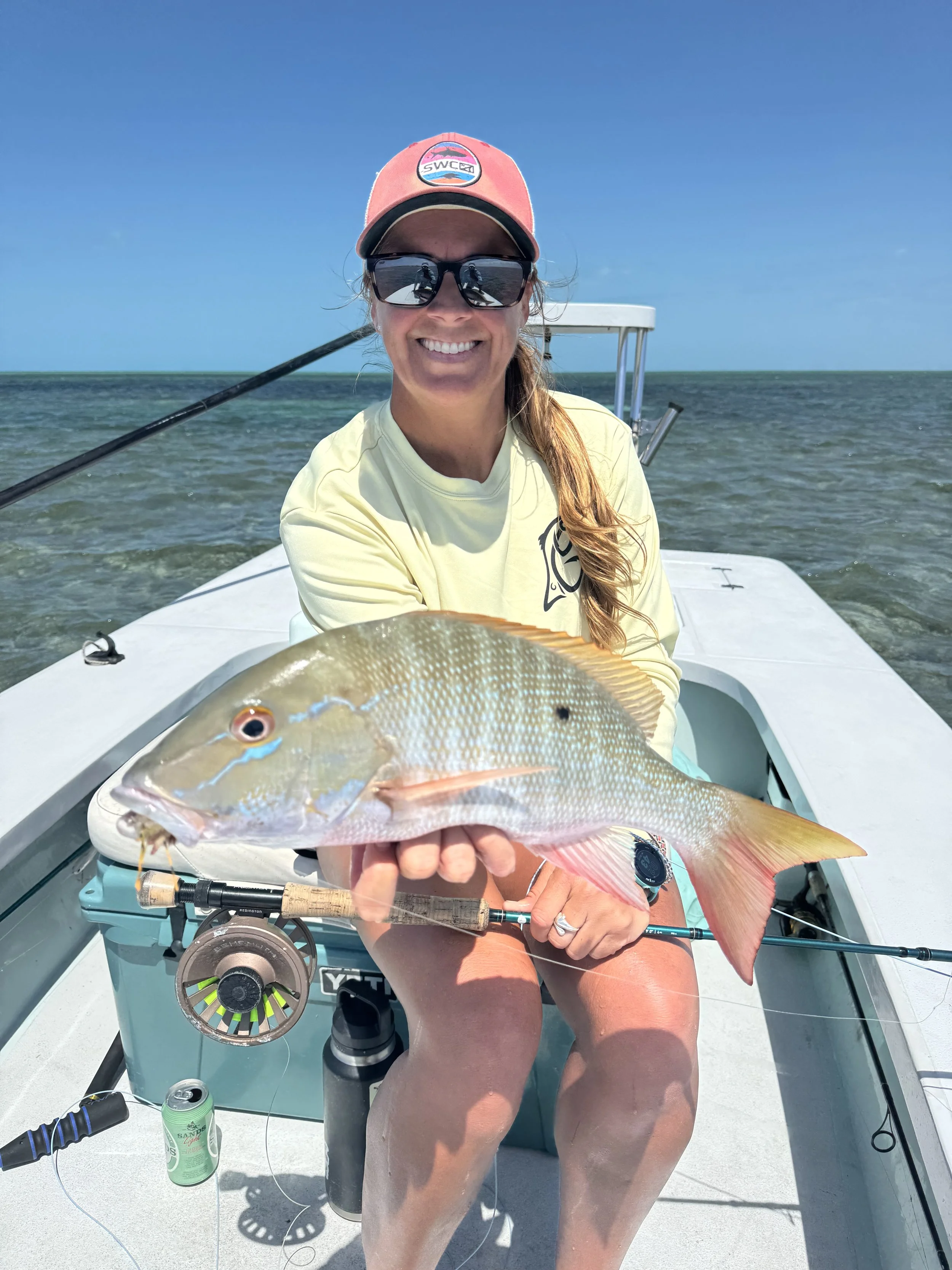 Angler holding a mutton snapper aboard a flats skiff in Grand Bahama, Bahamas.