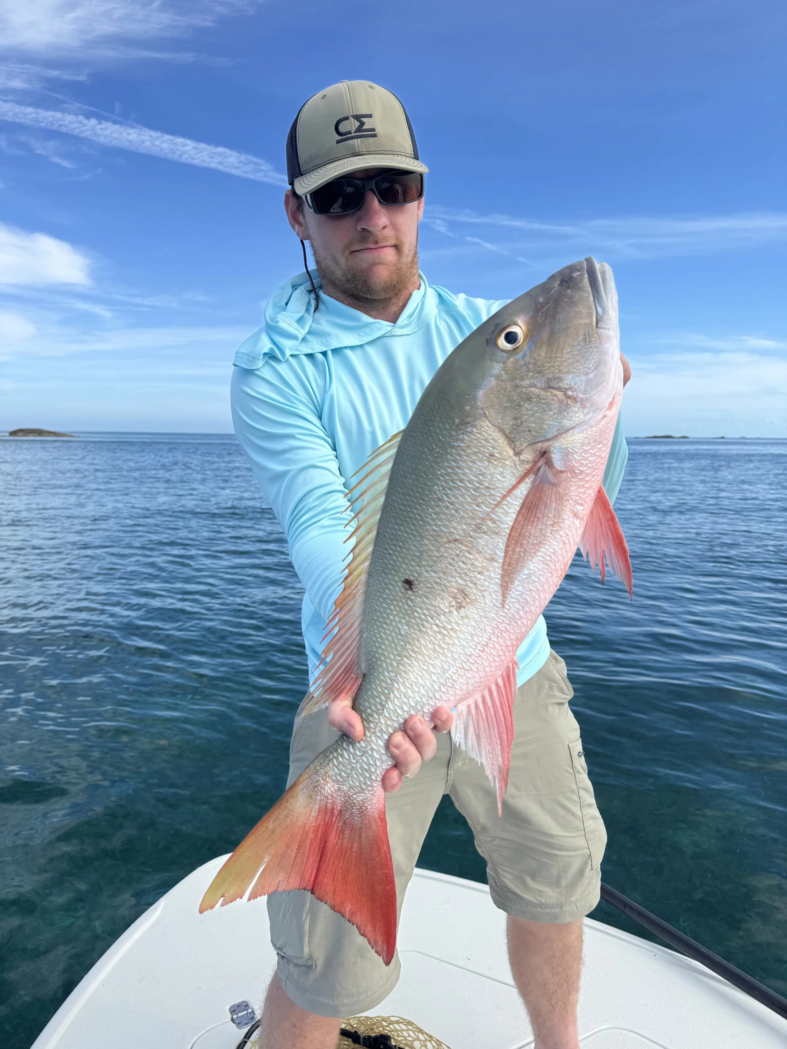Angler holding a large mutton snapper during a guided fishing trip in Grand Bahama, Bahamas.