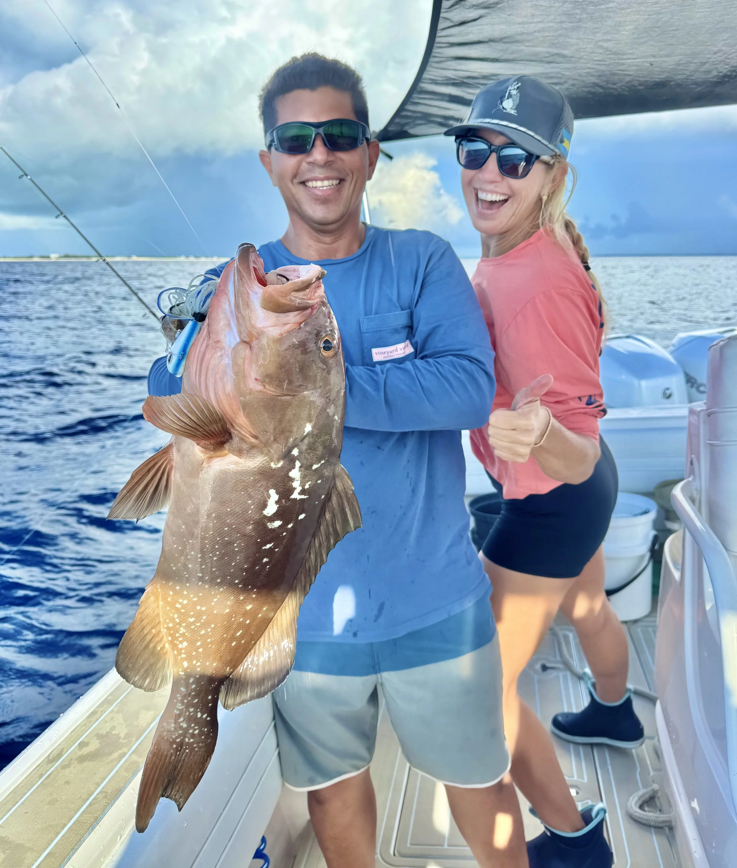 Anglers holding a large red grouper after a successful reef fishing trip in Abaco, Bahamas.