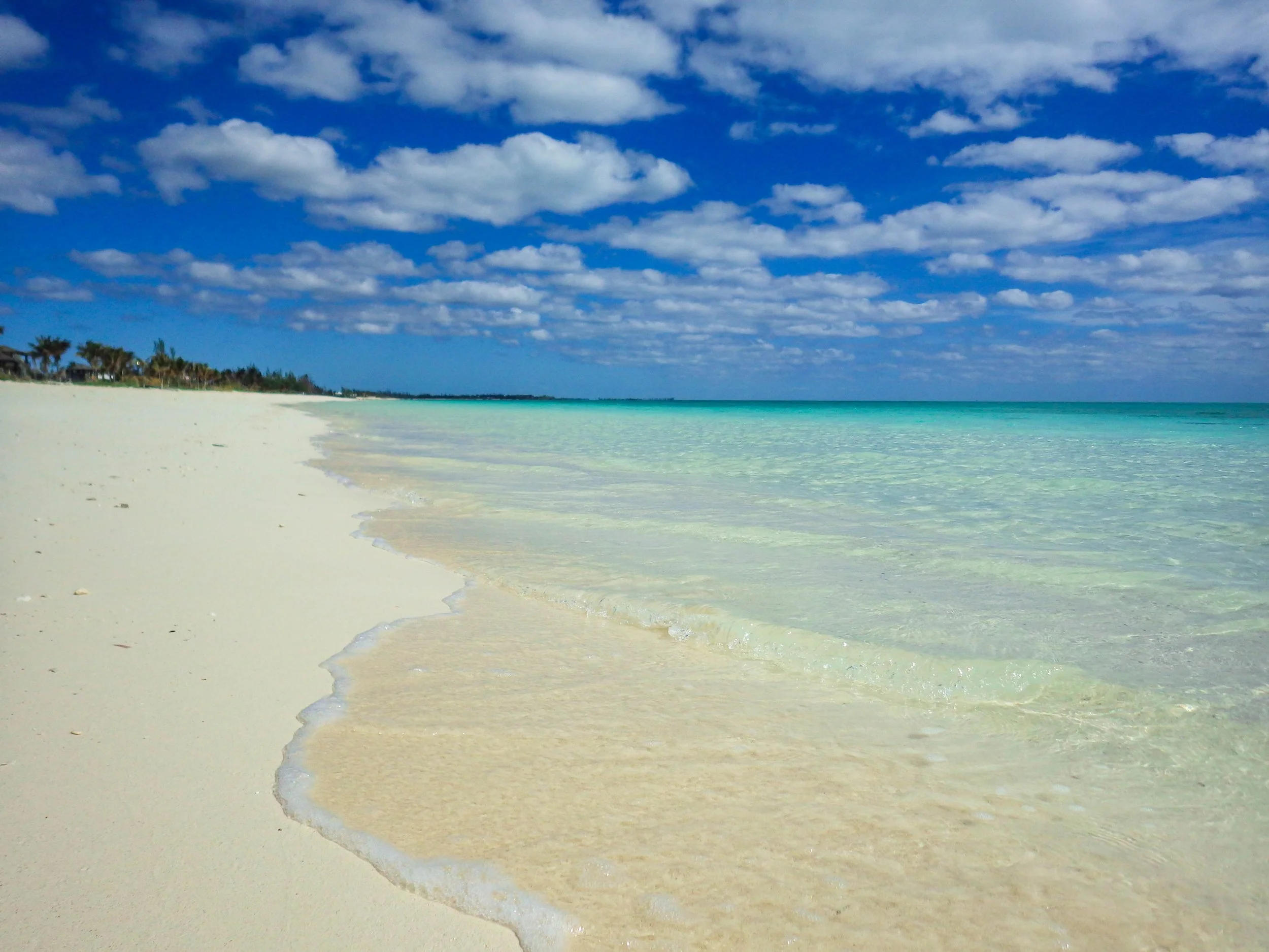 White-sand beach and shallow turquoise water in Freeport, Grand Bahama, Bahamas.