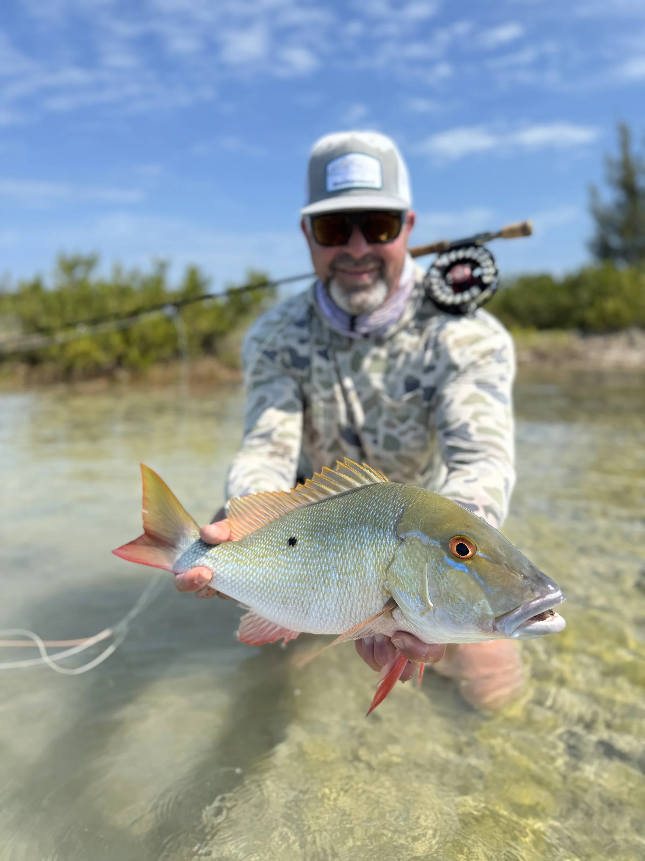 Angler holding a mutton snapper while fly fishing the shallow flats of Grand Bahama.