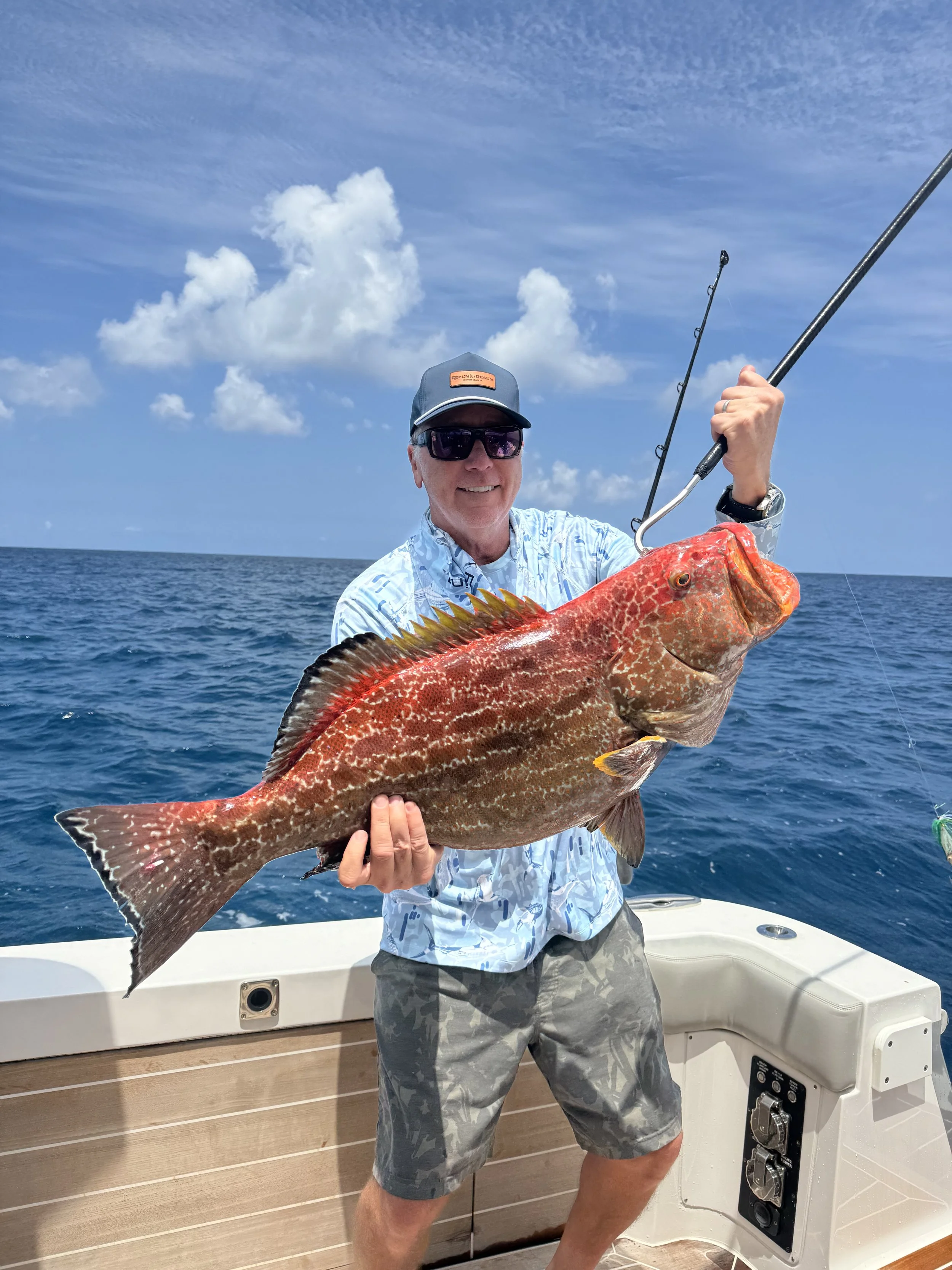 Angler holding a large grouper during an offshore fishing trip in Grand Bahama, Bahamas.