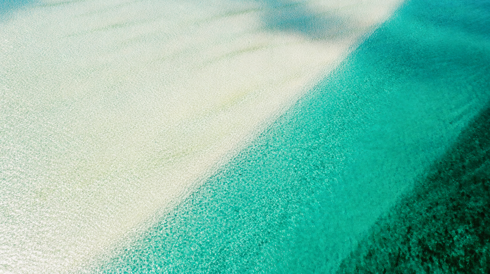 Aerial view of a white-sand flat meeting clear turquoise water in Grand Bahama.