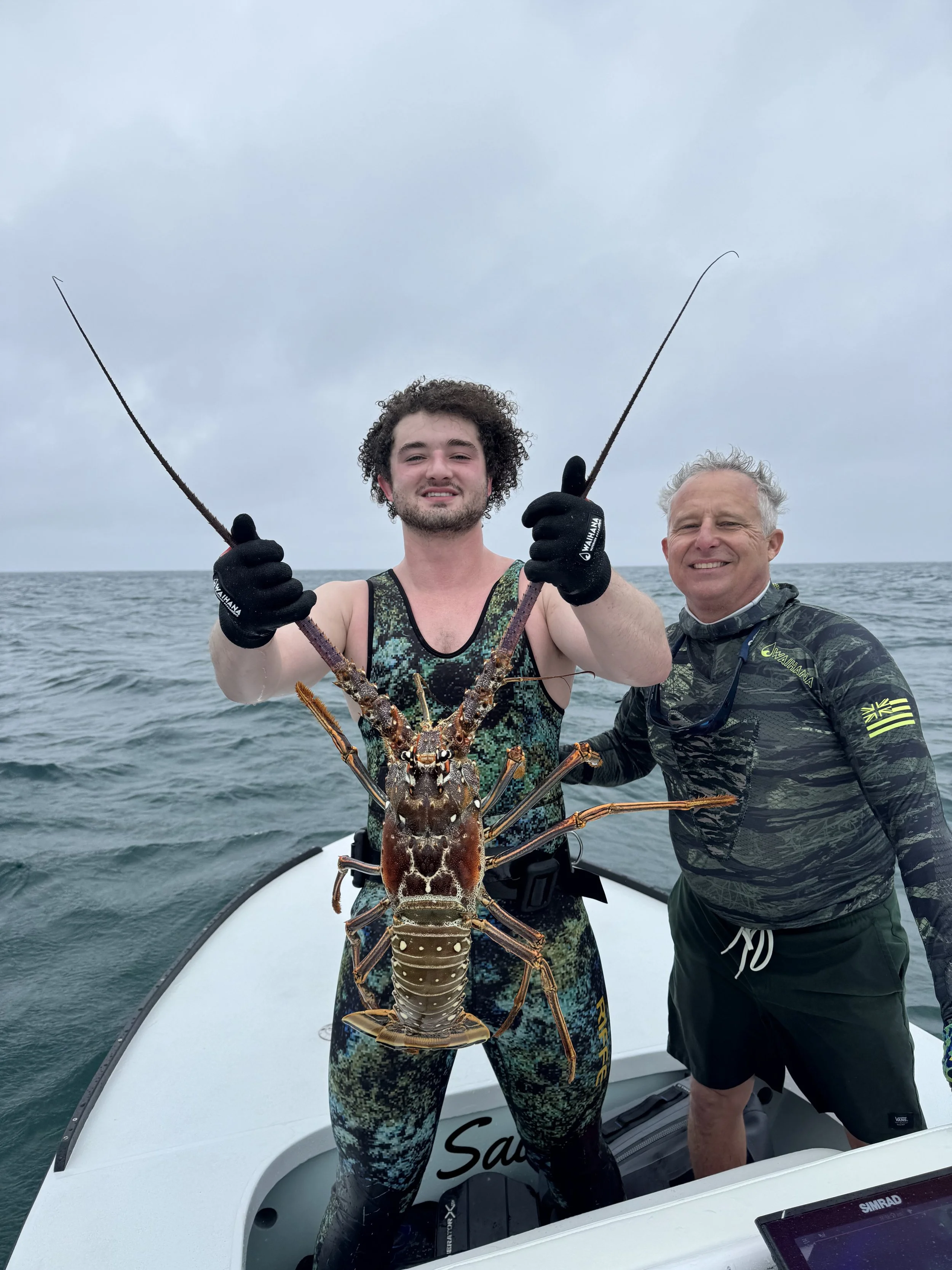 Divers holding a trophy Caribbean spiny lobster after a lobster diving trip in Grand Bahama, Bahamas.