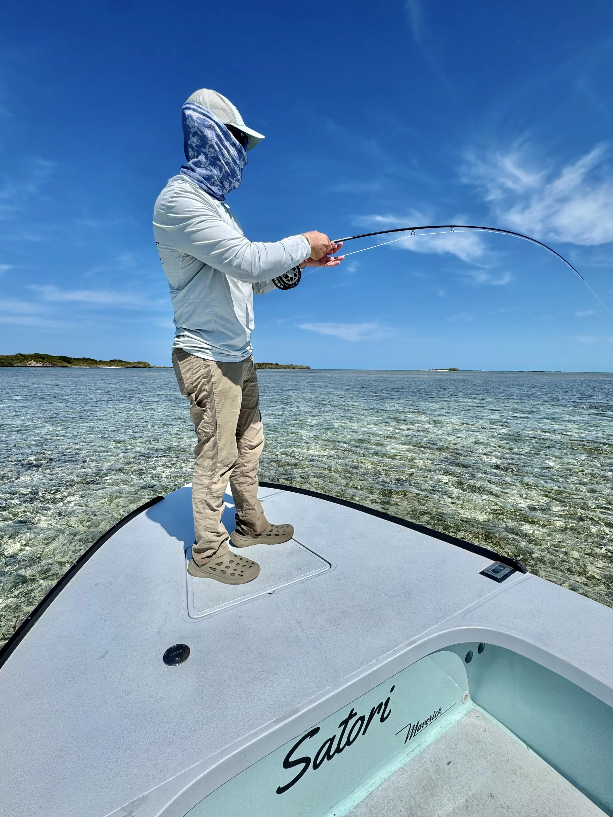 Angler fly fishing from the bow of a flats boat in the shallow clear waters of The Bahamas with Goombay Outfitters.