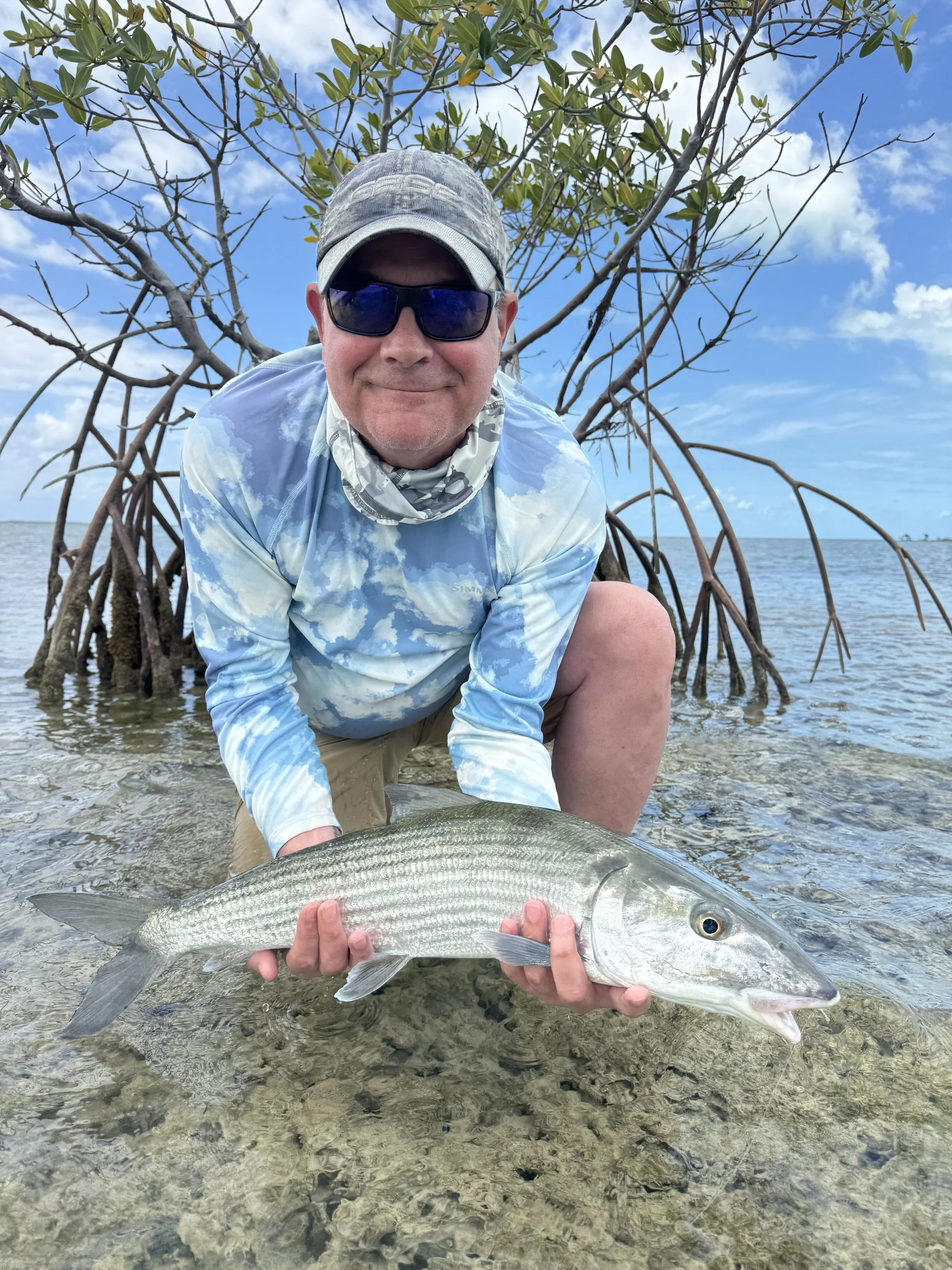 Angler holding a bonefish beside mangrove habitat in Grand Bahama, Bahamas.