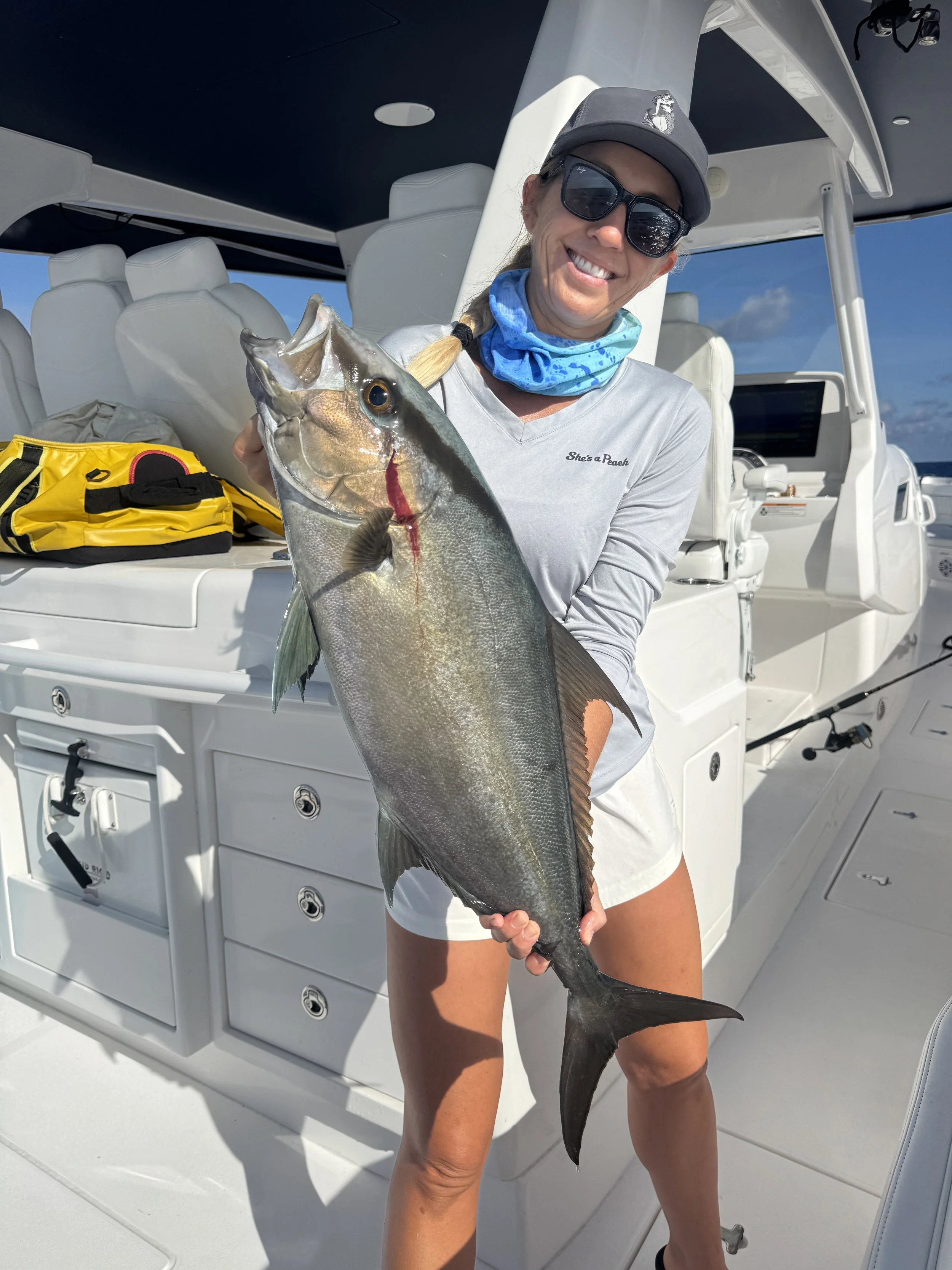 Angler holding a large almaco jack caught while reef fishing in Abaco, Bahamas.