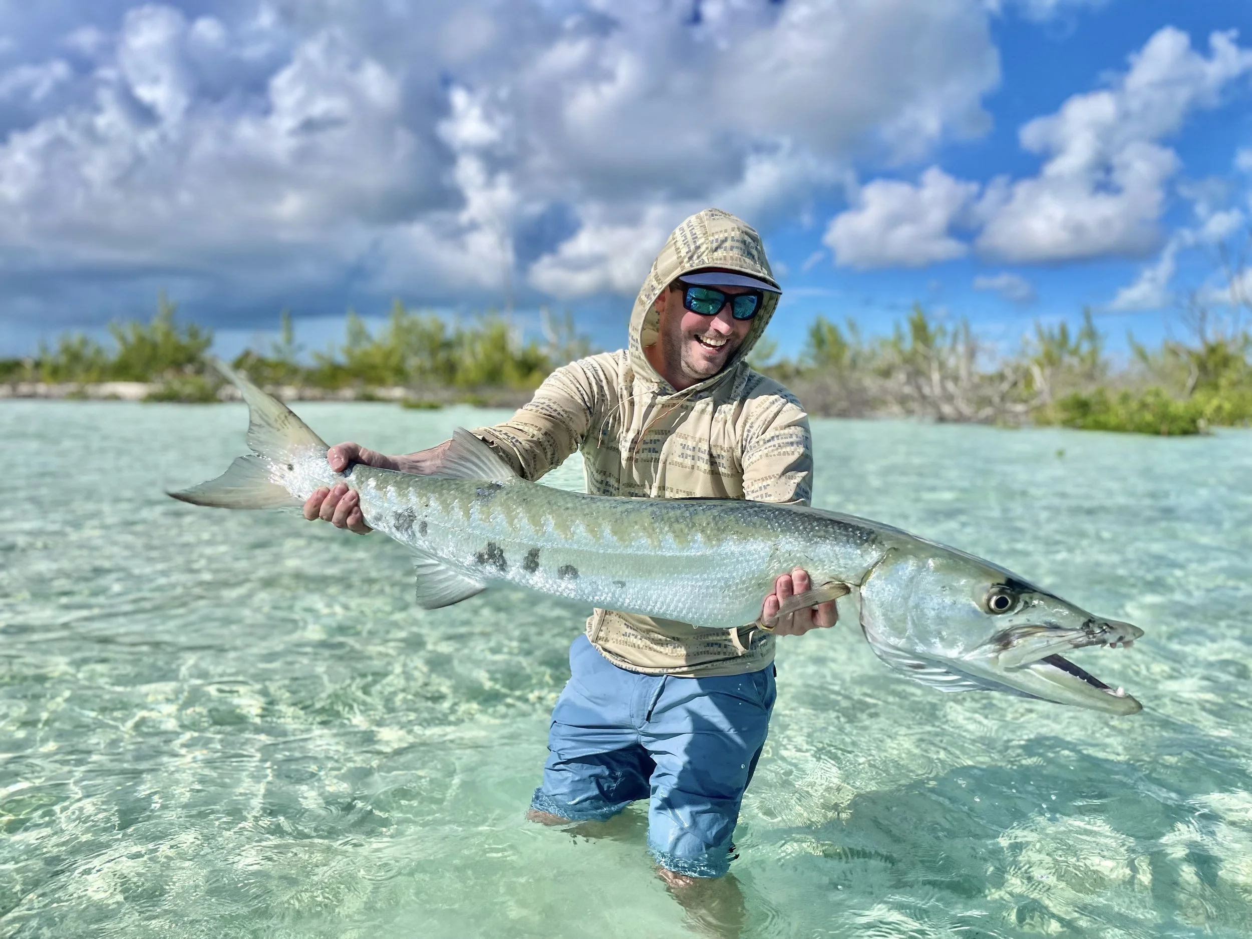 Angler holding a large barracuda while fishing a shallow flat in Grand Bahama.