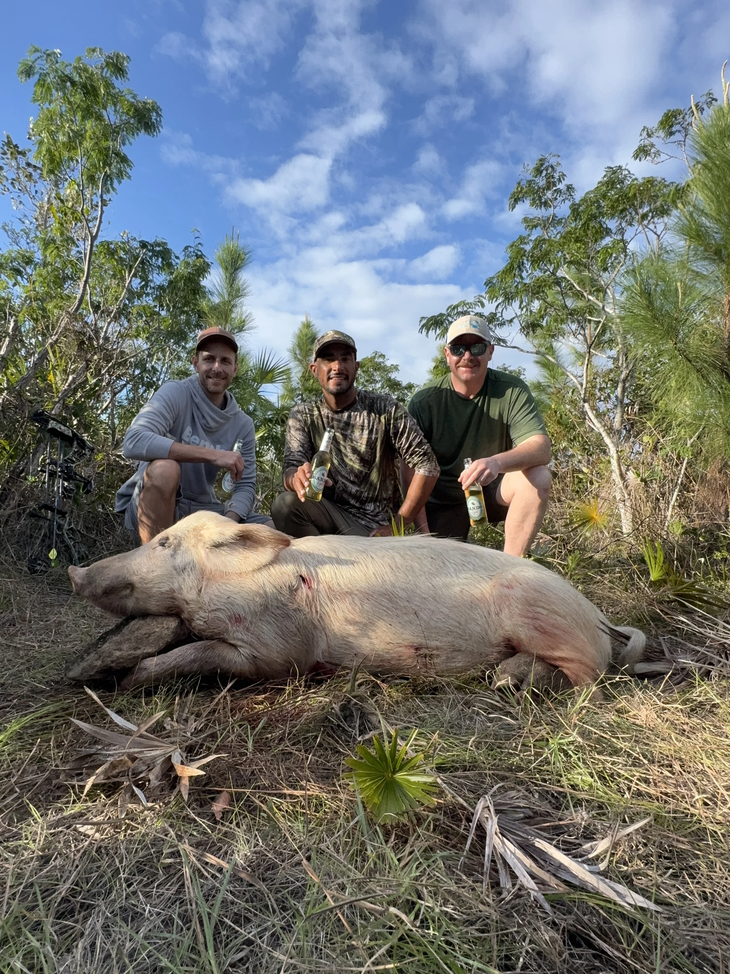 Hunters and guide Justin Lewis posing with a harvested wild hog during a guided hunt in Grand Bahama, Bahamas.