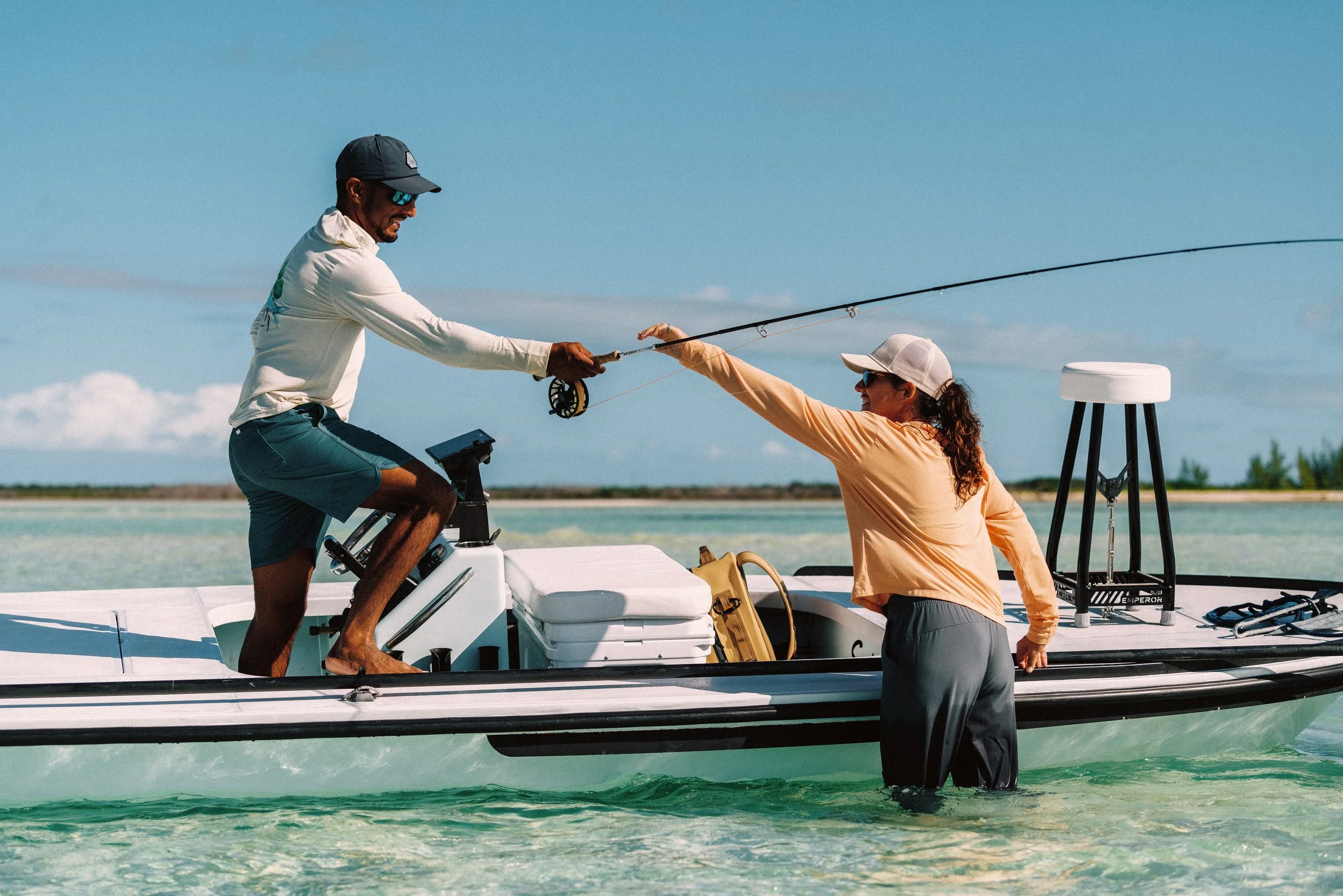 Guide handing angler fly rod beside a flats skiff during a successful flats fishing trip in Grand Bahama.