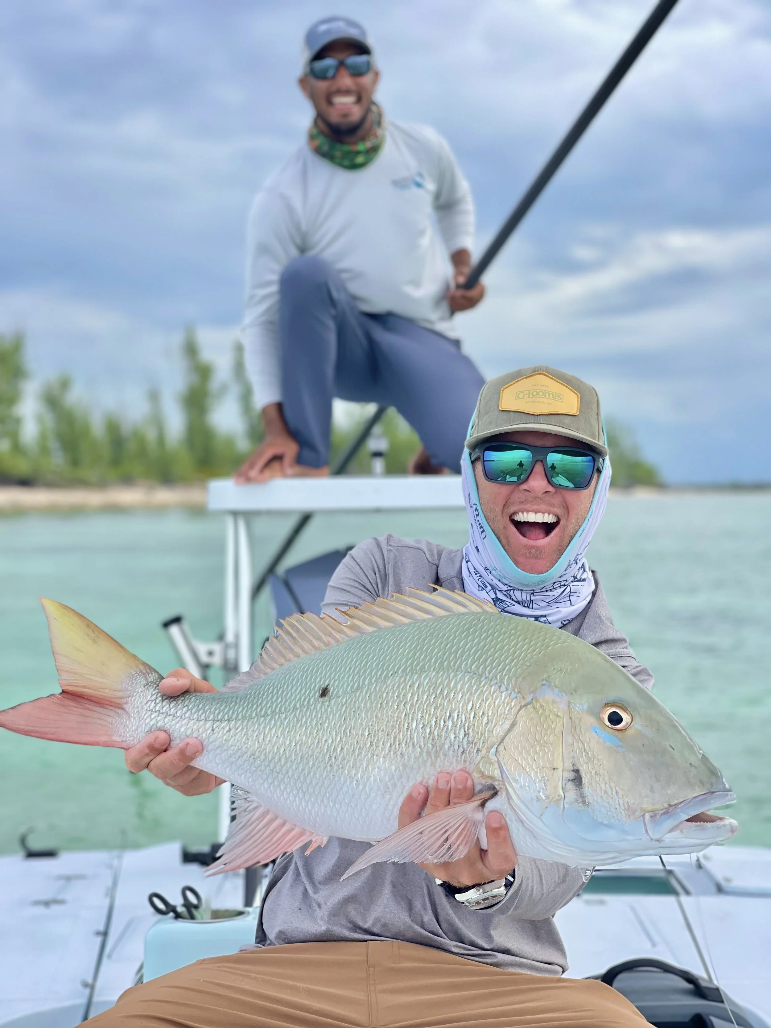 Angler holding a mutton snapper aboard a flats boat while fishing the shallow waters of The Bahamas.