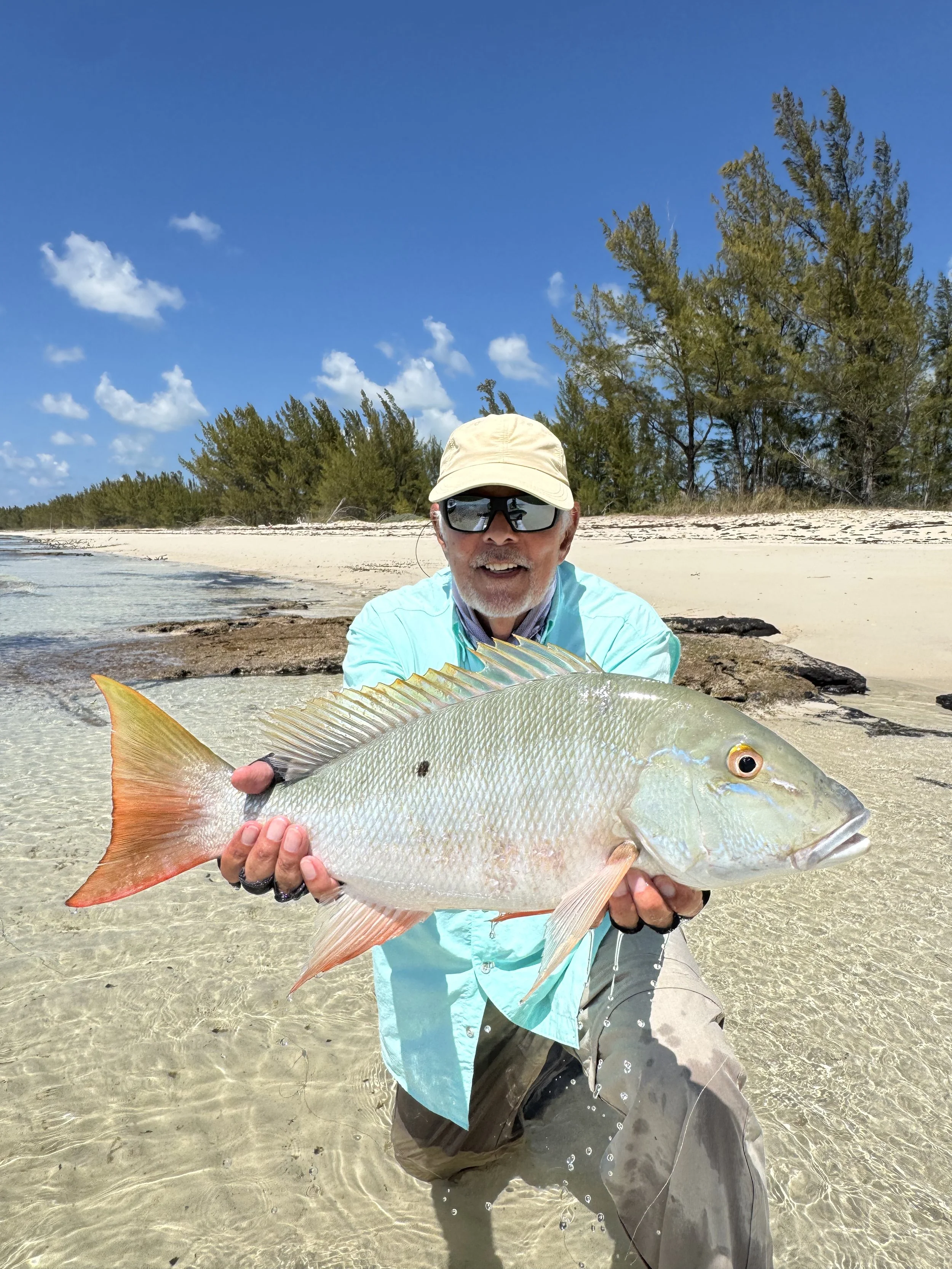 Angler holding a large mutton snapper caught in the shallow waters of Grand Bahama, Bahamas.