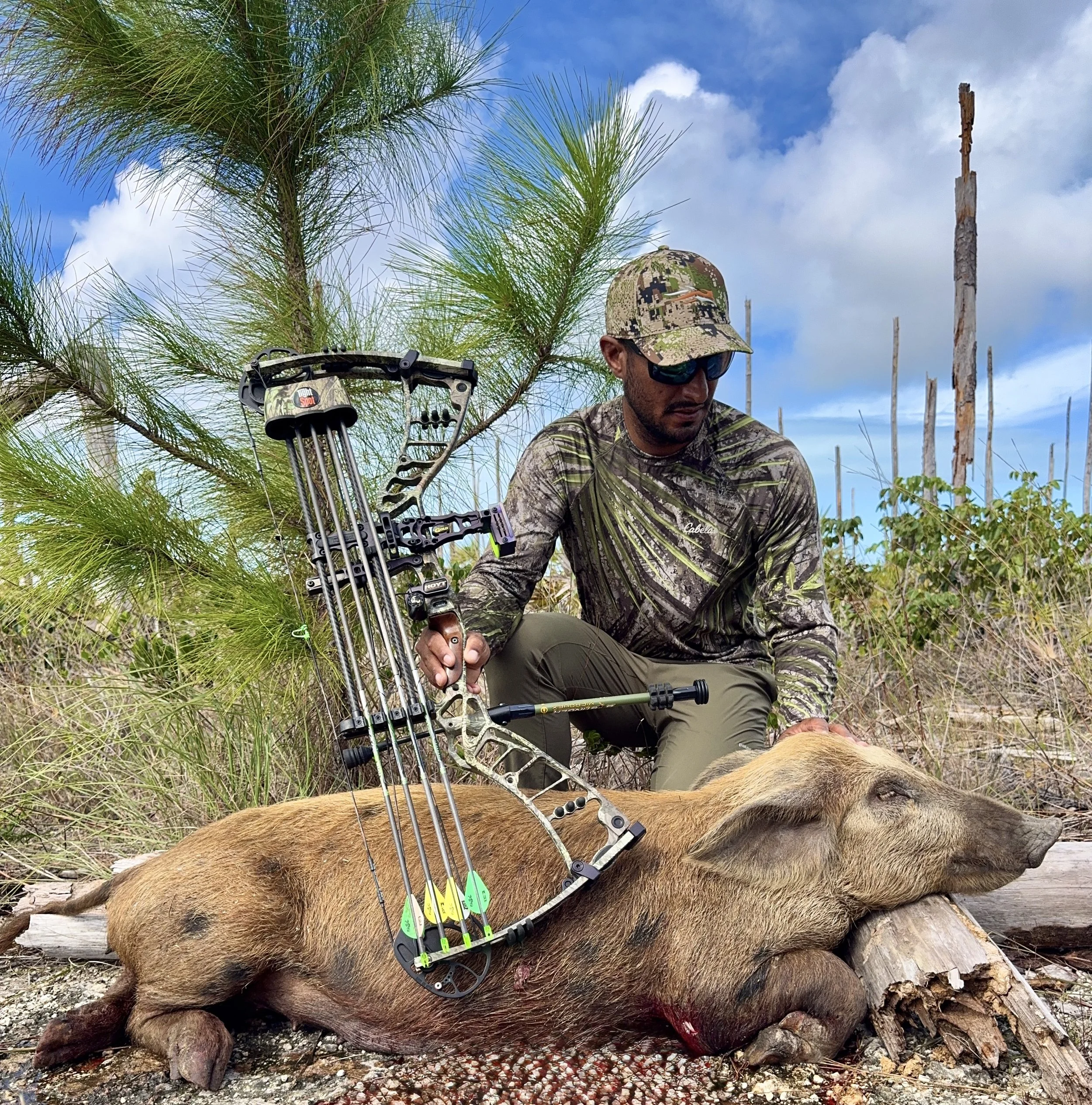 Hunter with bow beside a wild hog during a guided trip in Grand Bahama, Bahamas.