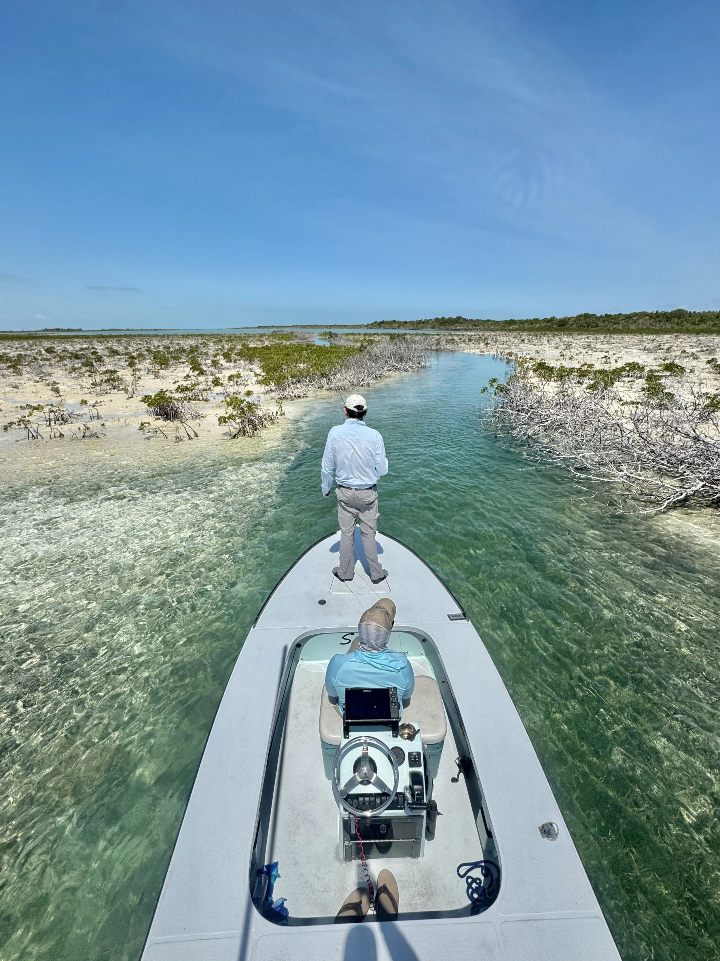 Flats skiff navigating a narrow shallow-water creek through the backcountry of Grand Bahama and Abaco.