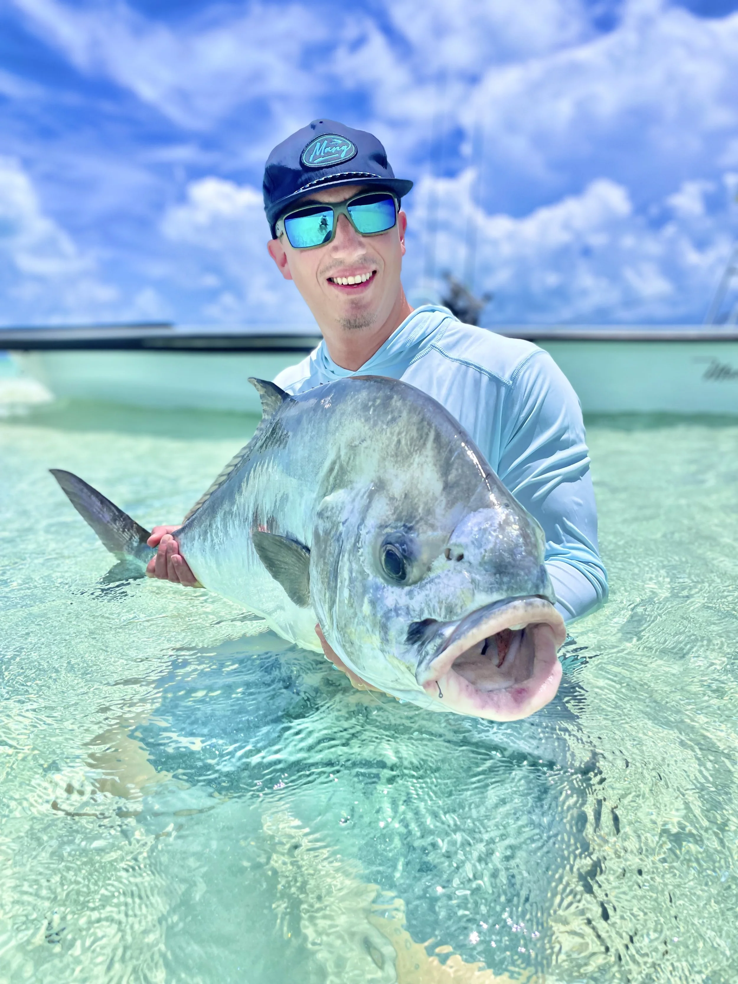 Angler holding a large permit in the clear shallow waters of Grand Bahama, Bahamas.