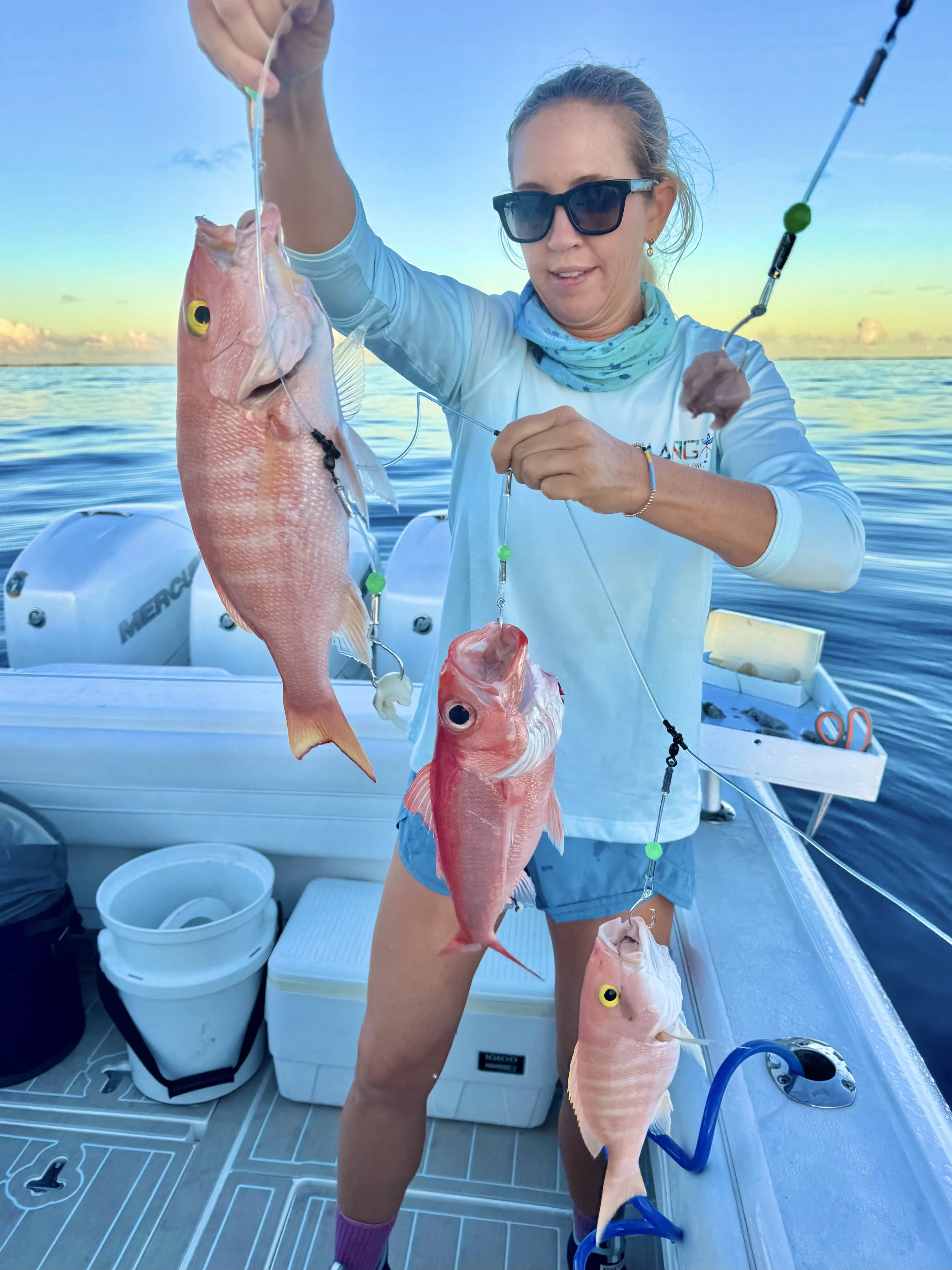 Angler displaying freshly caught deepwater queen and yellow-eye snapper aboard a fishing boat in Abaco, Bahamas.