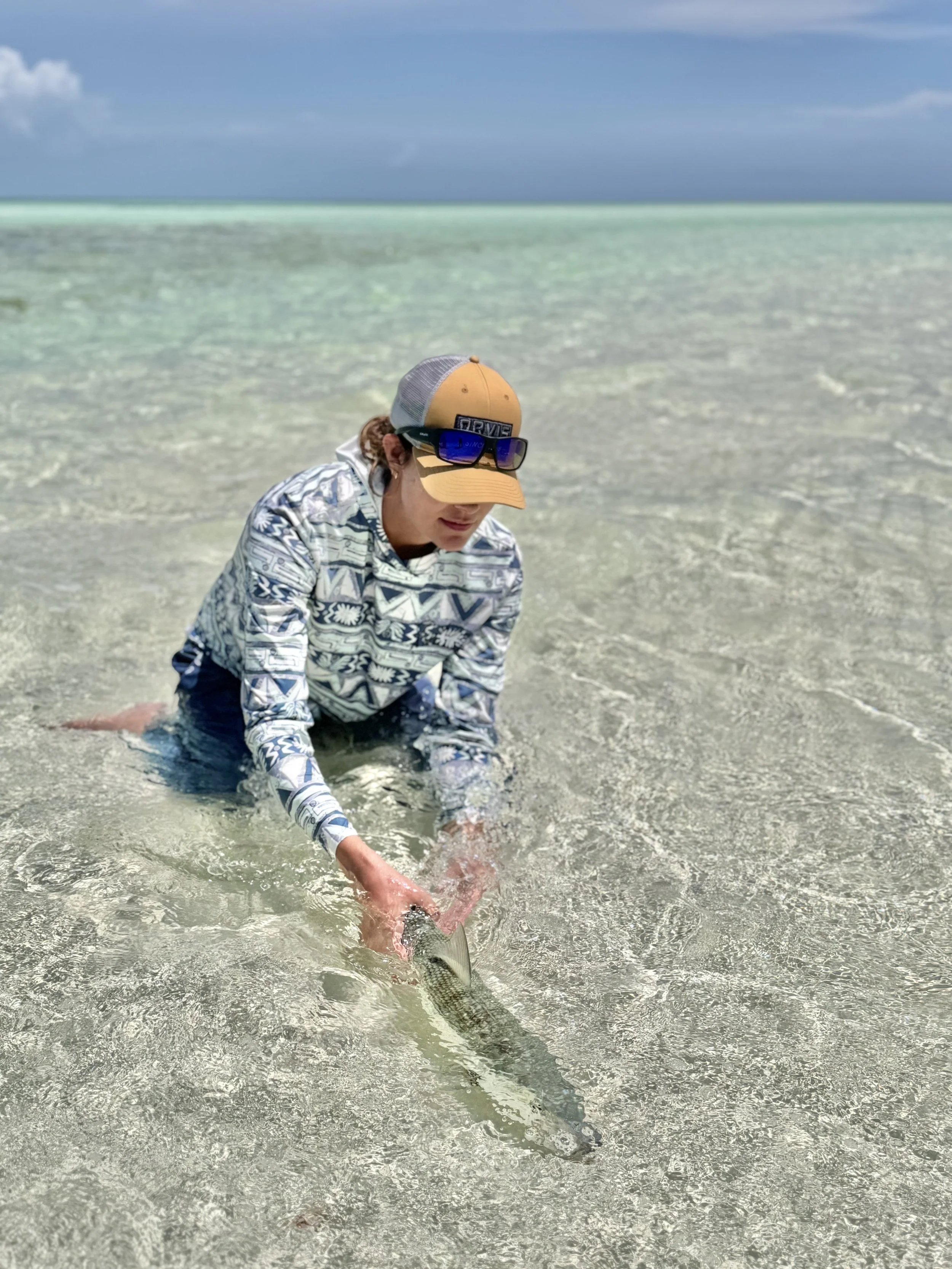 Angler releasing bonefish while fly fishing a shallow flat in Grand Bahama.