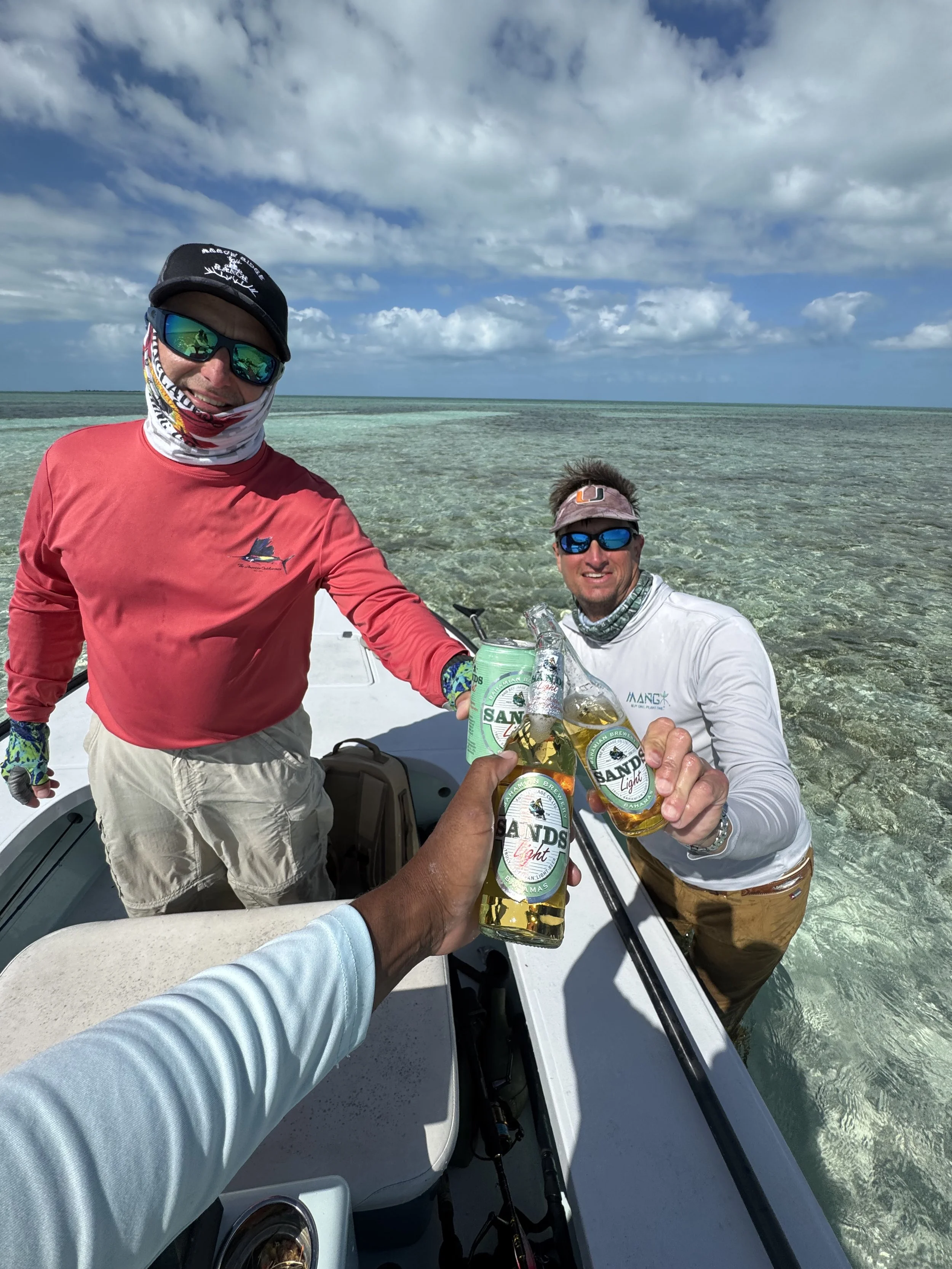 Guests relaxing with cold beers aboard a flats skiff after a successful day of fishing in Grand Bahama.
