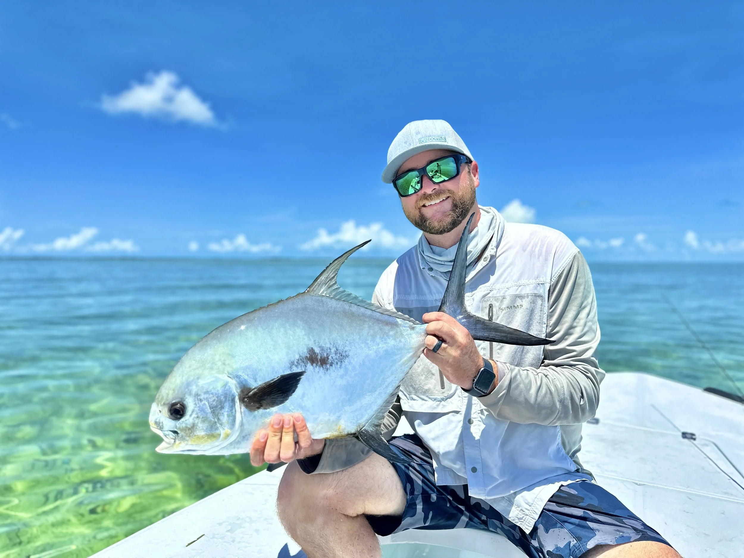Angler holding a permit aboard a flats skiff in the clear waters of Grand Bahama.