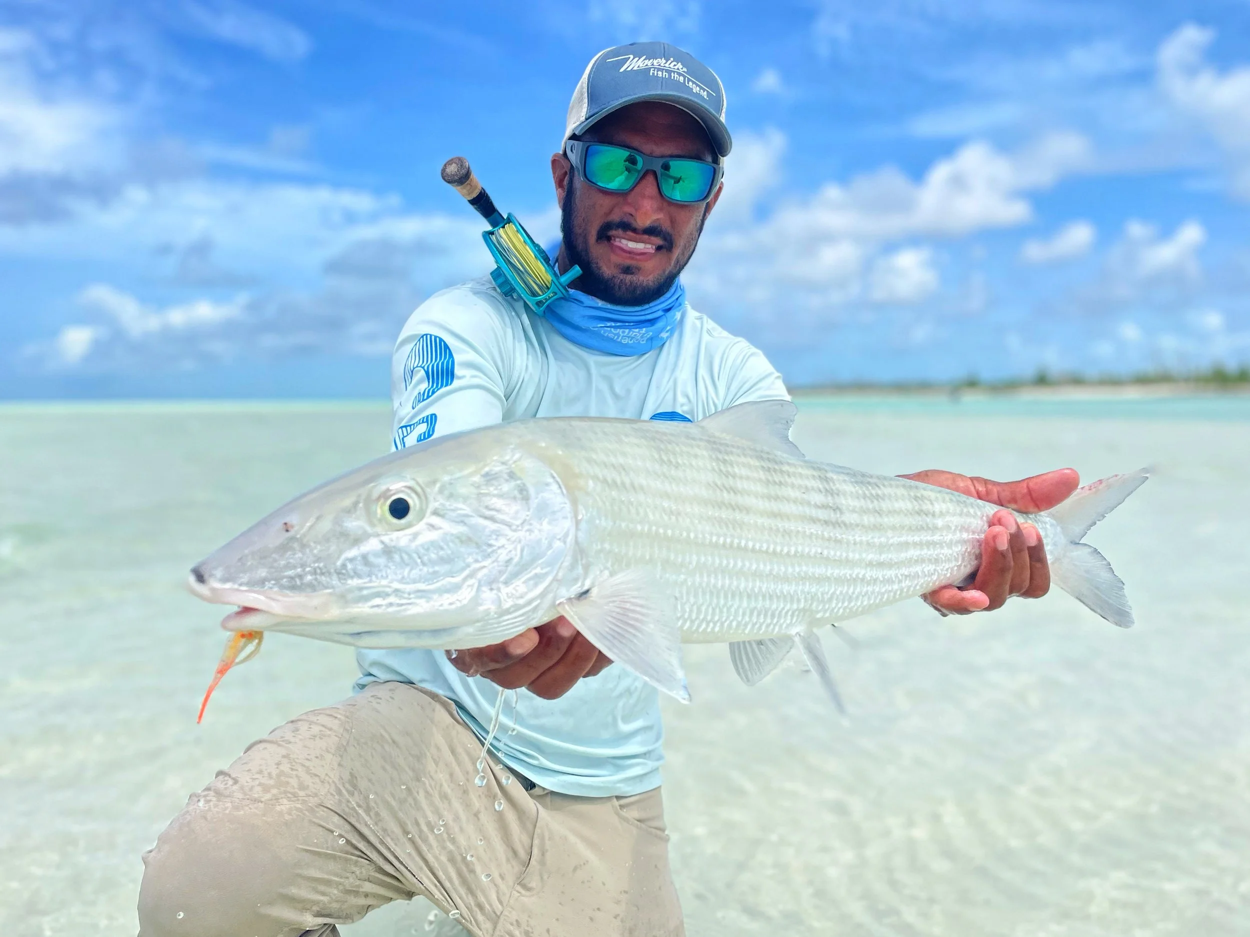 Angler holding a large bonefish while fly fishing a white-sand flat in Abaco.
