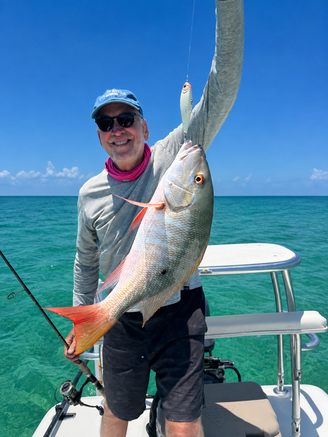Angler holding a mutton snapper aboard a boat in the waters of Grand Bahama.