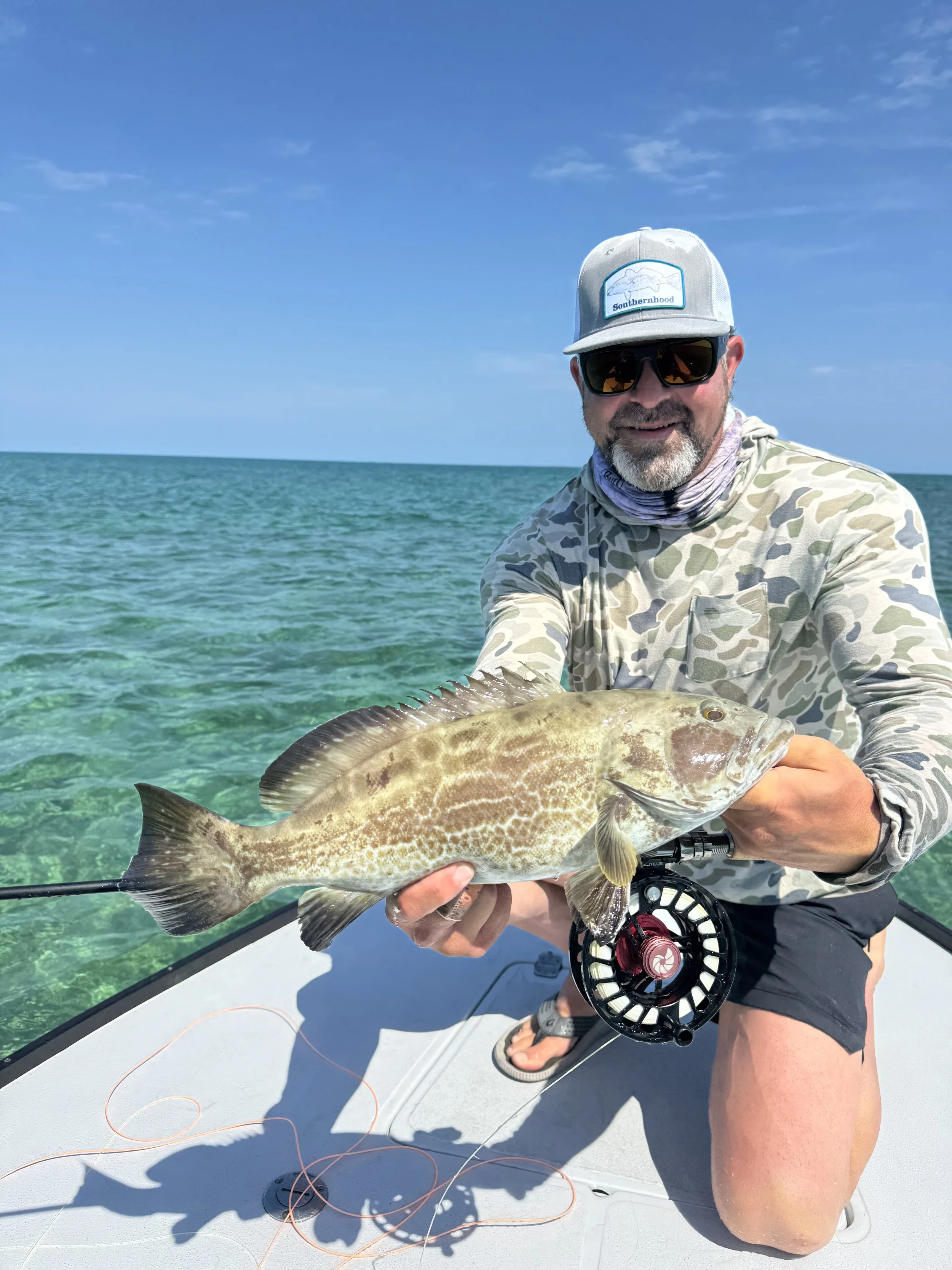 Angler holding a grouper caught while fly fishing the reefs of Abaco.