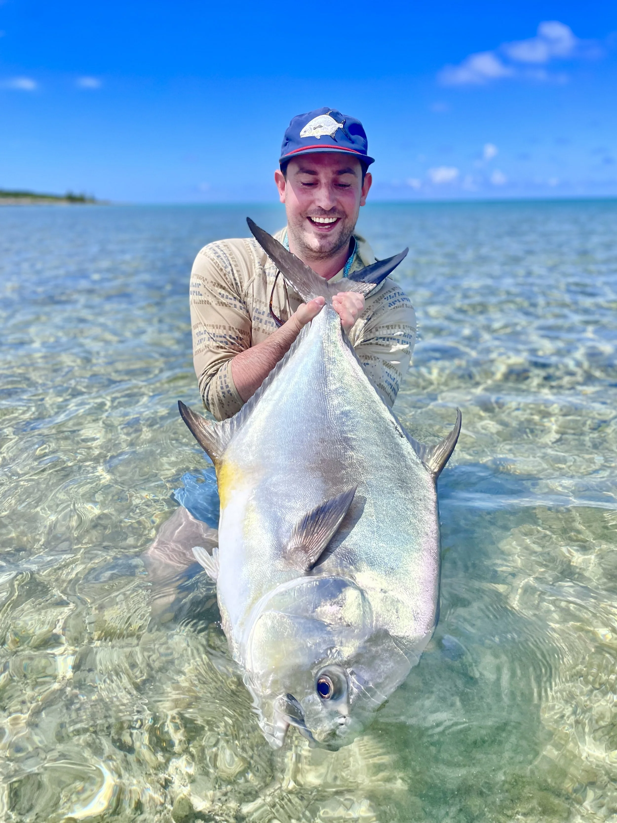 Angler holding a large permit while light tackle fishing a shallow flat in Grand Bahama.