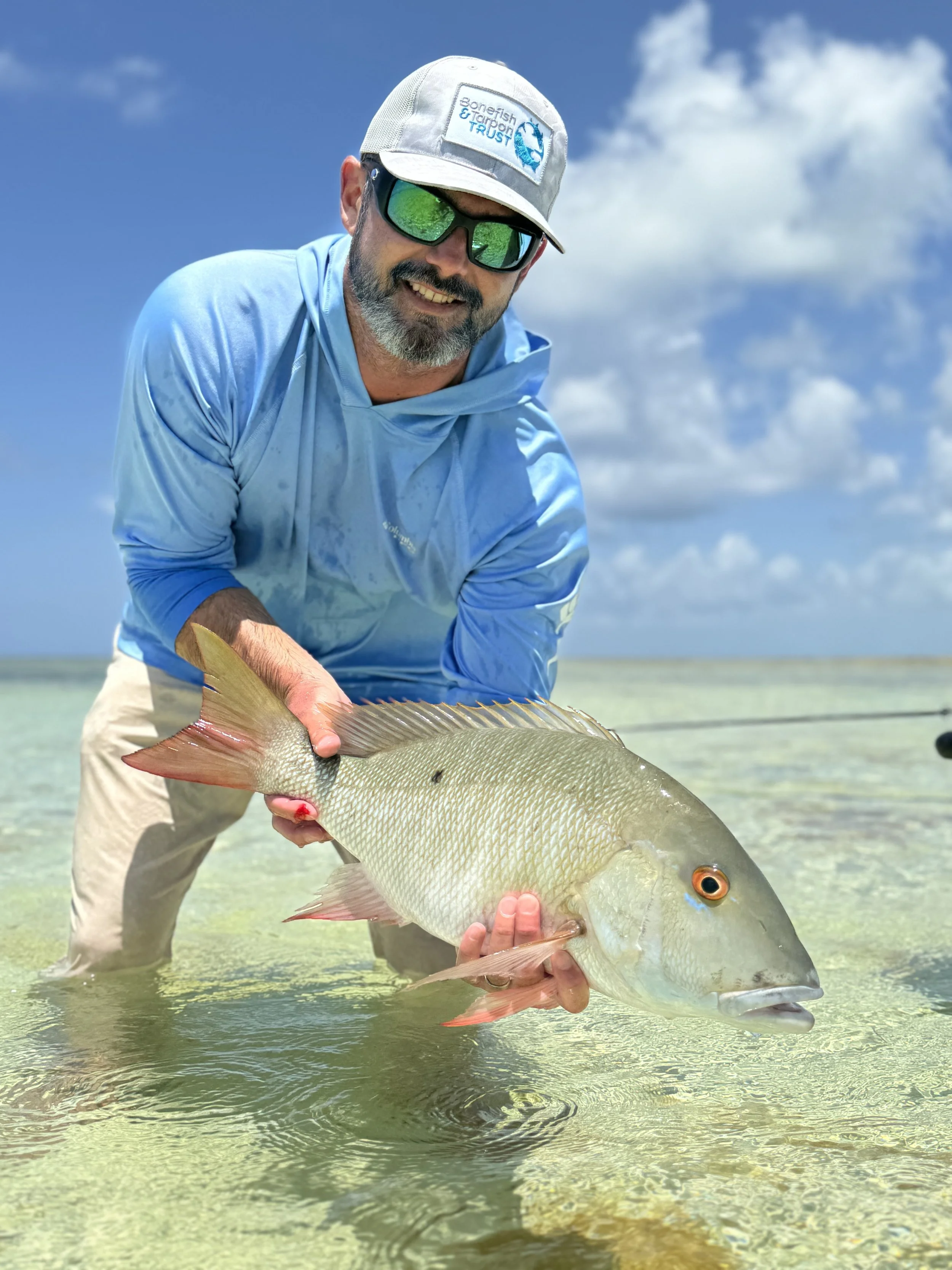 Angler holding a mutton snapper while fly fishing the shallow flats of Grand Bahama, Bahamas.