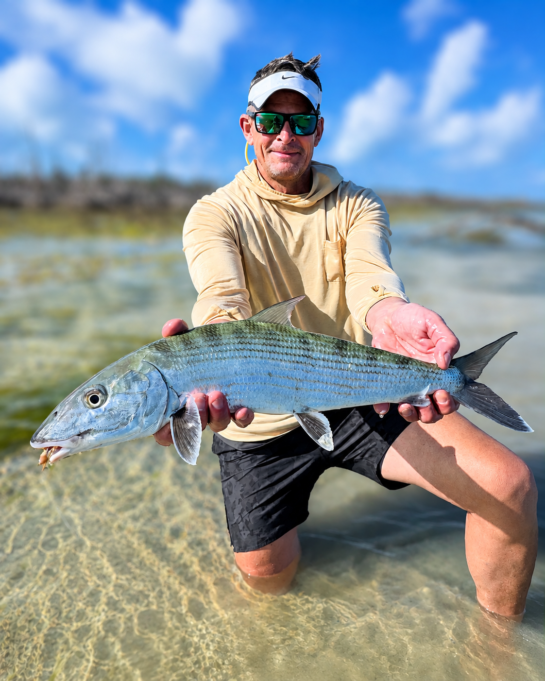 Angler holding a trophy bonefish while fly fishing a shallow flat in Grand Bahama, The Bahamas.